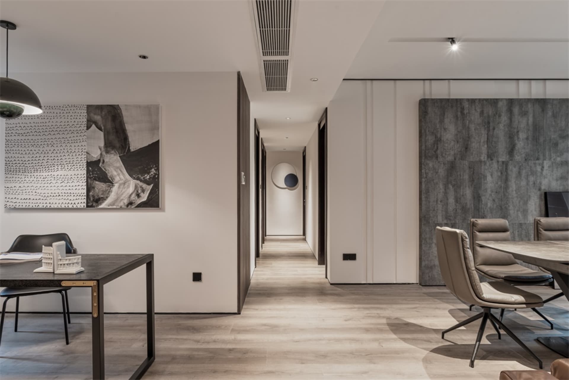 Modern dining room with mixed materials, including a wooden floor, black and white abstract painting, concrete finish wall, a