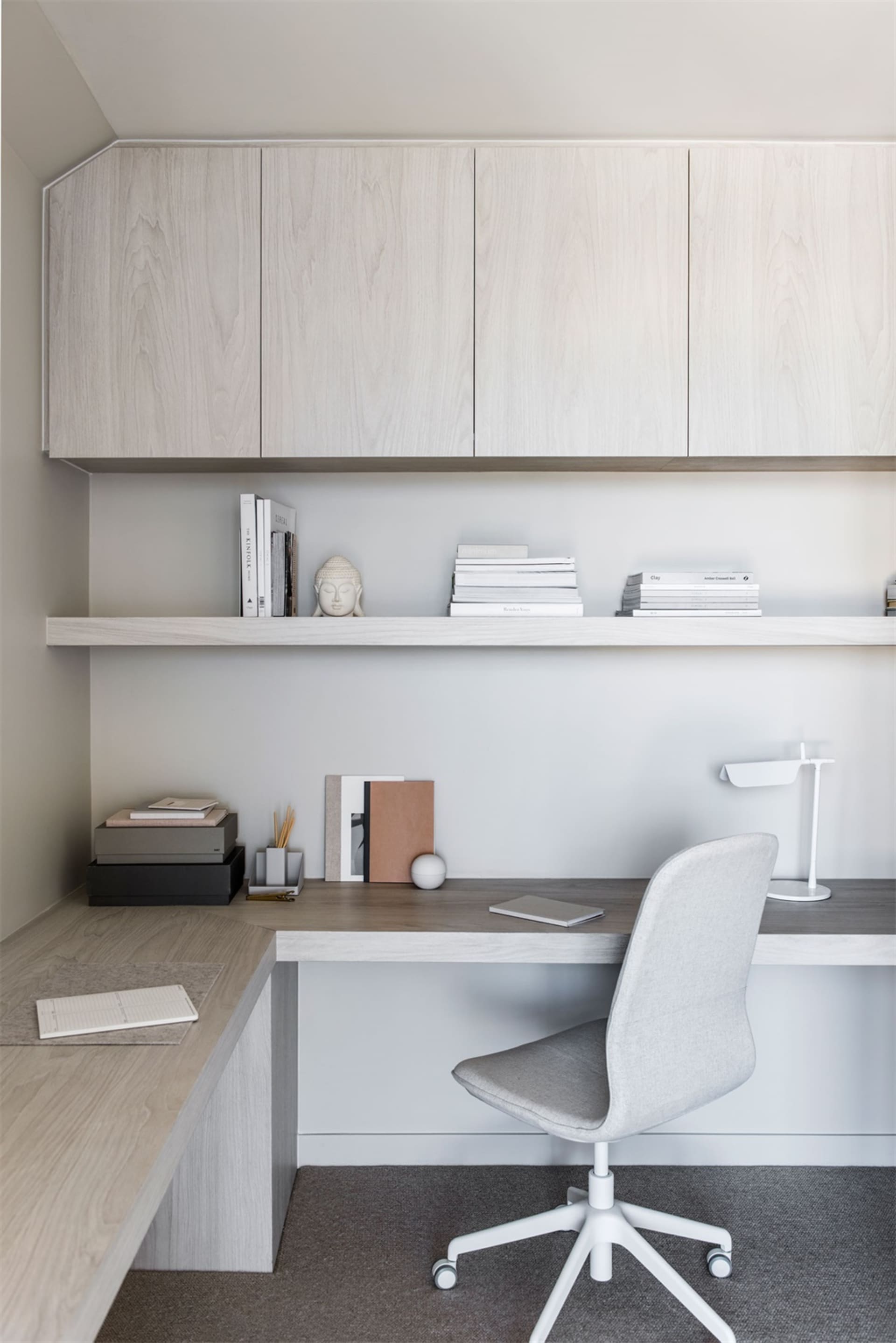 Modern home office featuring a wooden desk and chair, with built-in shelves and cabinets.
