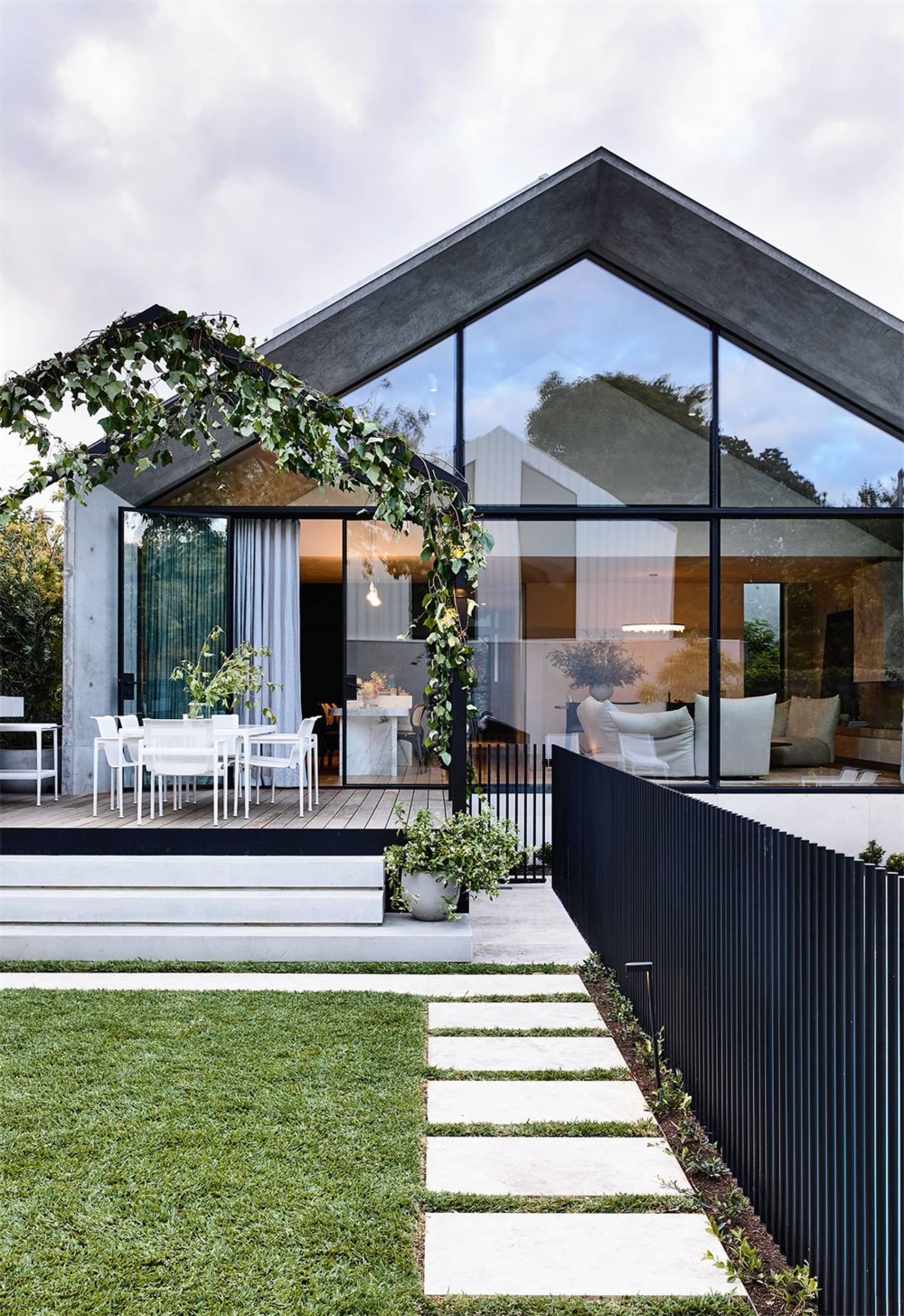 Modern minimalist house exterior with concrete structure, large glass windows, and green plant decor