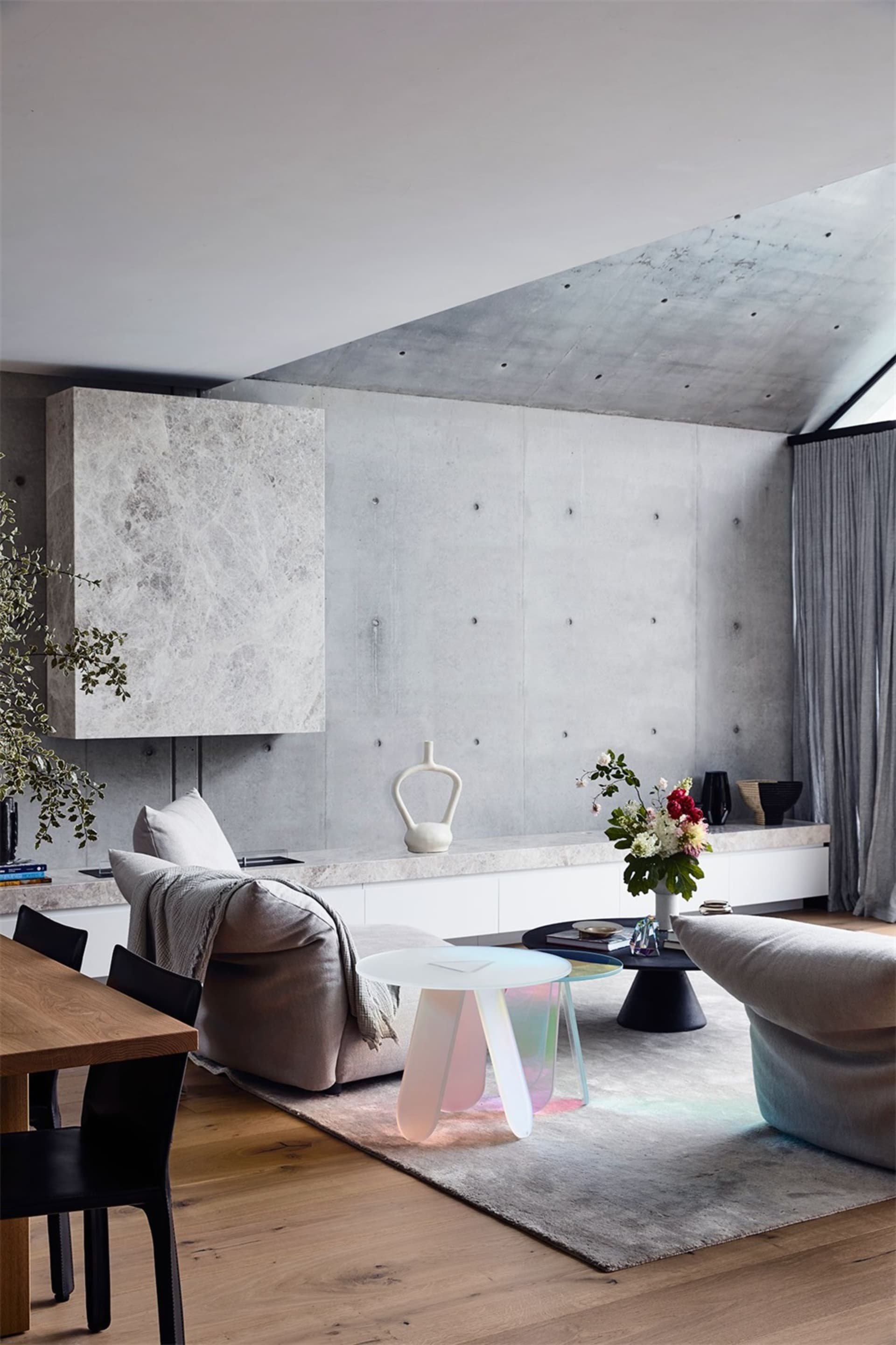 A modern living room with concrete walls, wooden flooring, and contemporary furniture and design elements.
