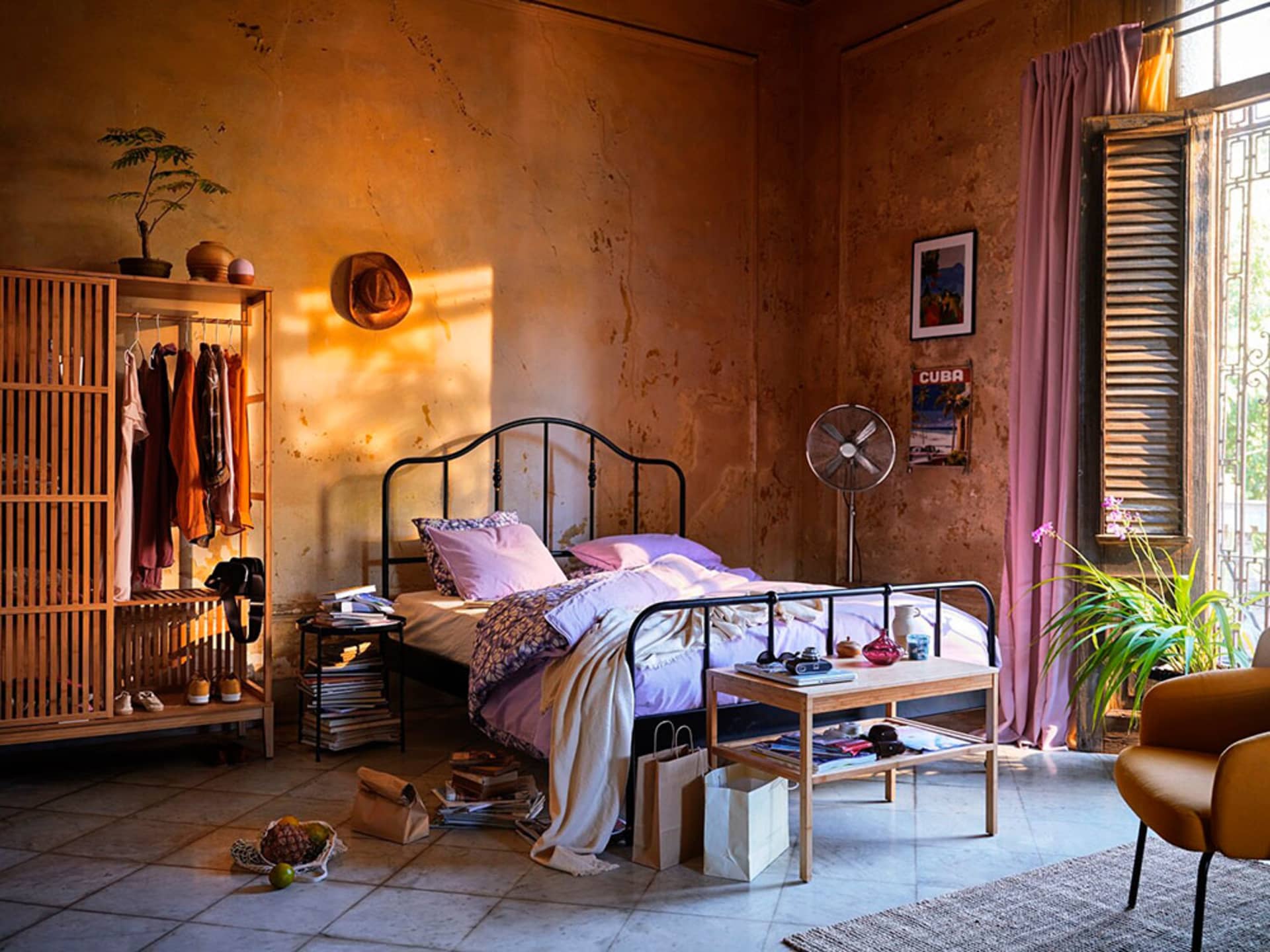 An industrial-style bedroom with a metal bed frame, wooden wardrobe, and concrete walls.