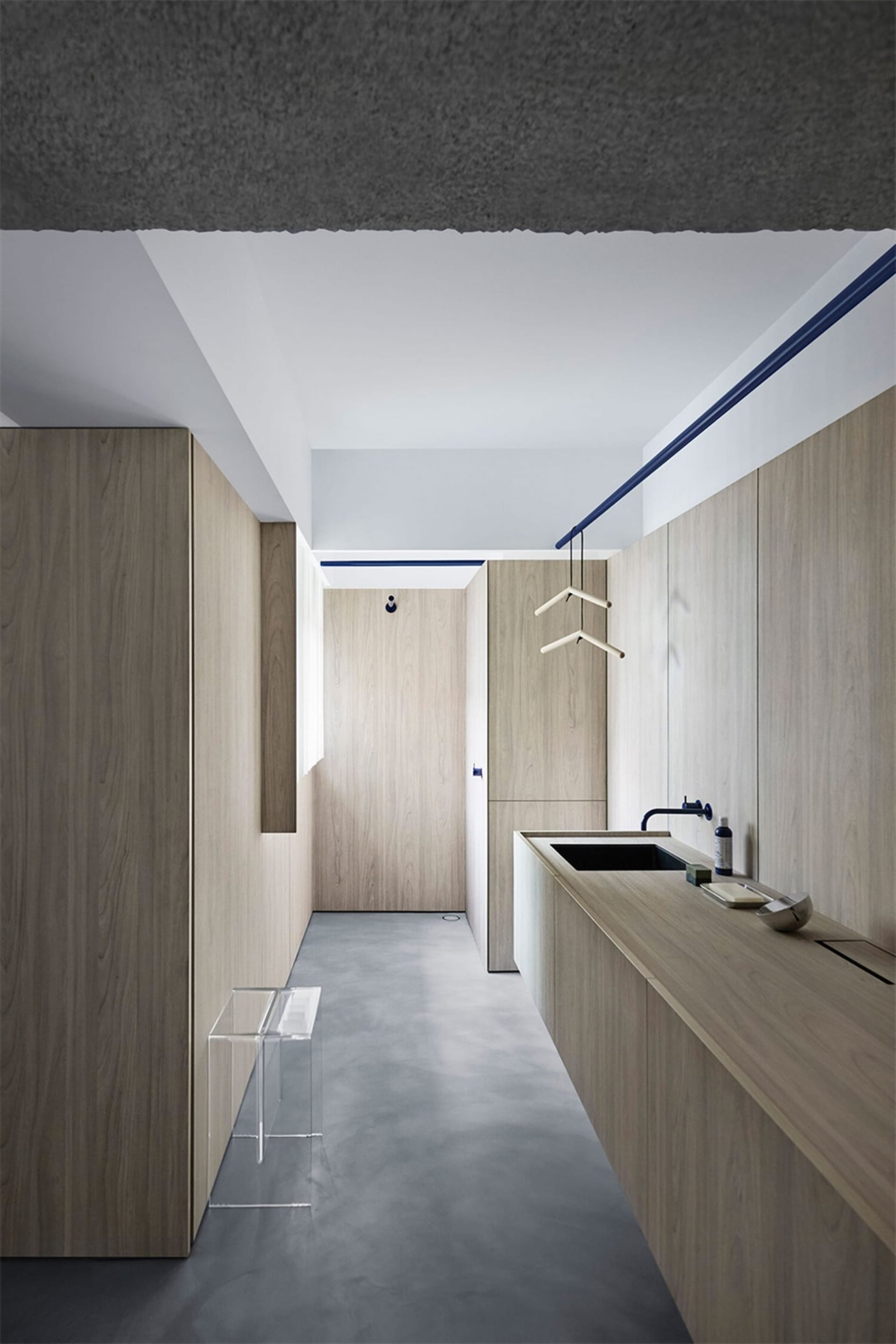 A modern minimalist entryway with wooden paneling and concrete flooring.