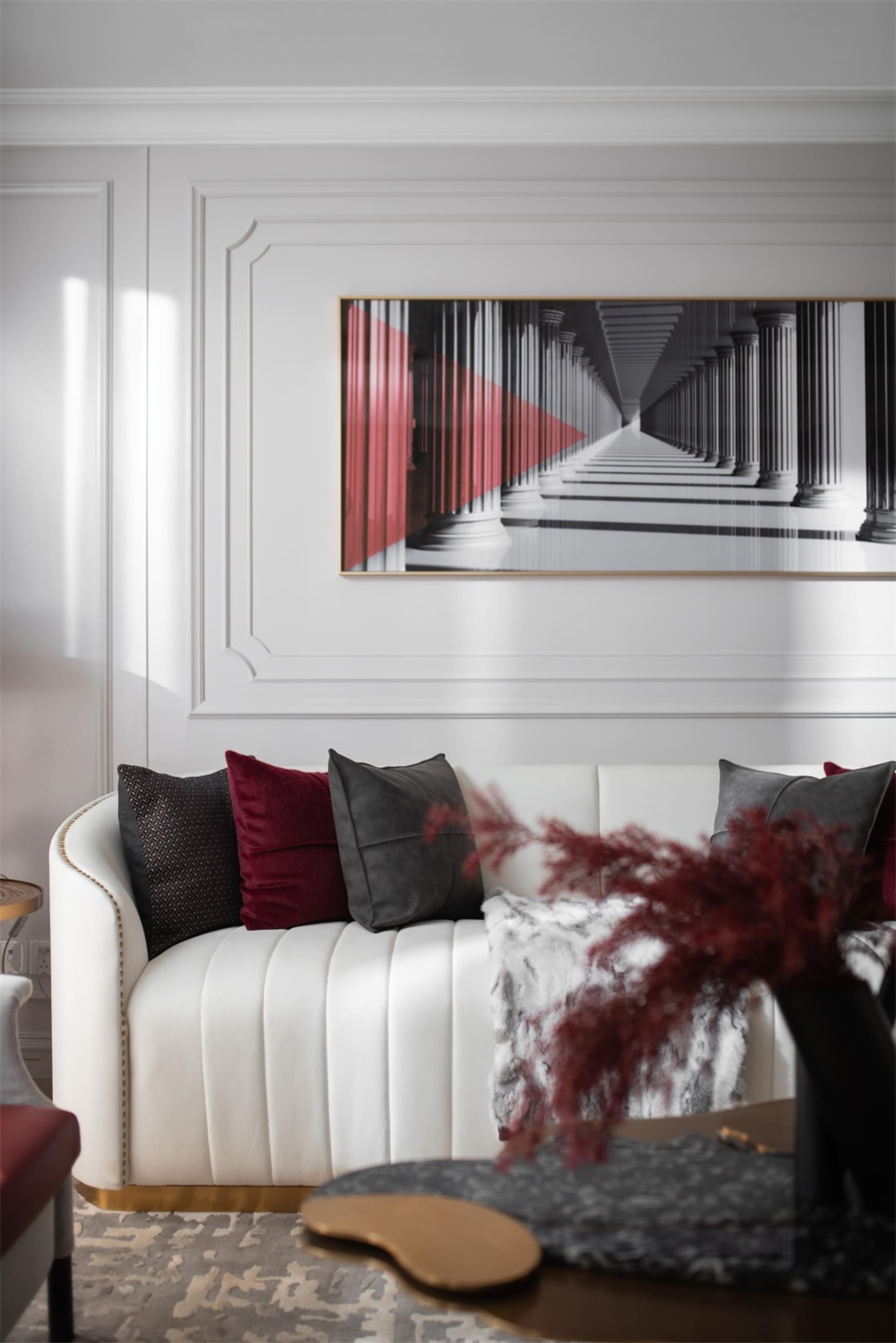Modern living room featuring a white sofa, red accent pillows, and a red and white abstract painting on the wall.