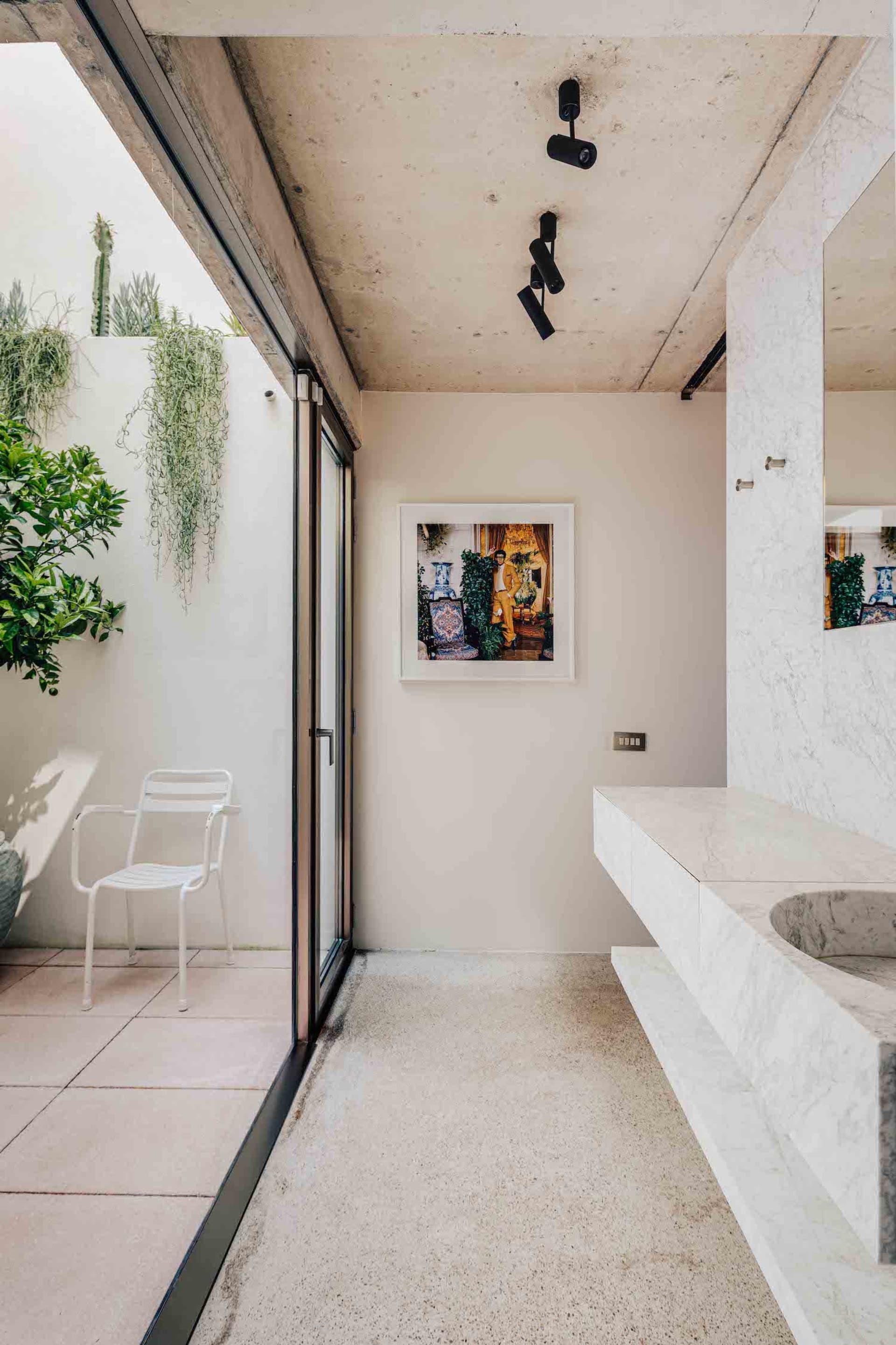 Modern minimalist bathroom with marble countertops and concrete floor.