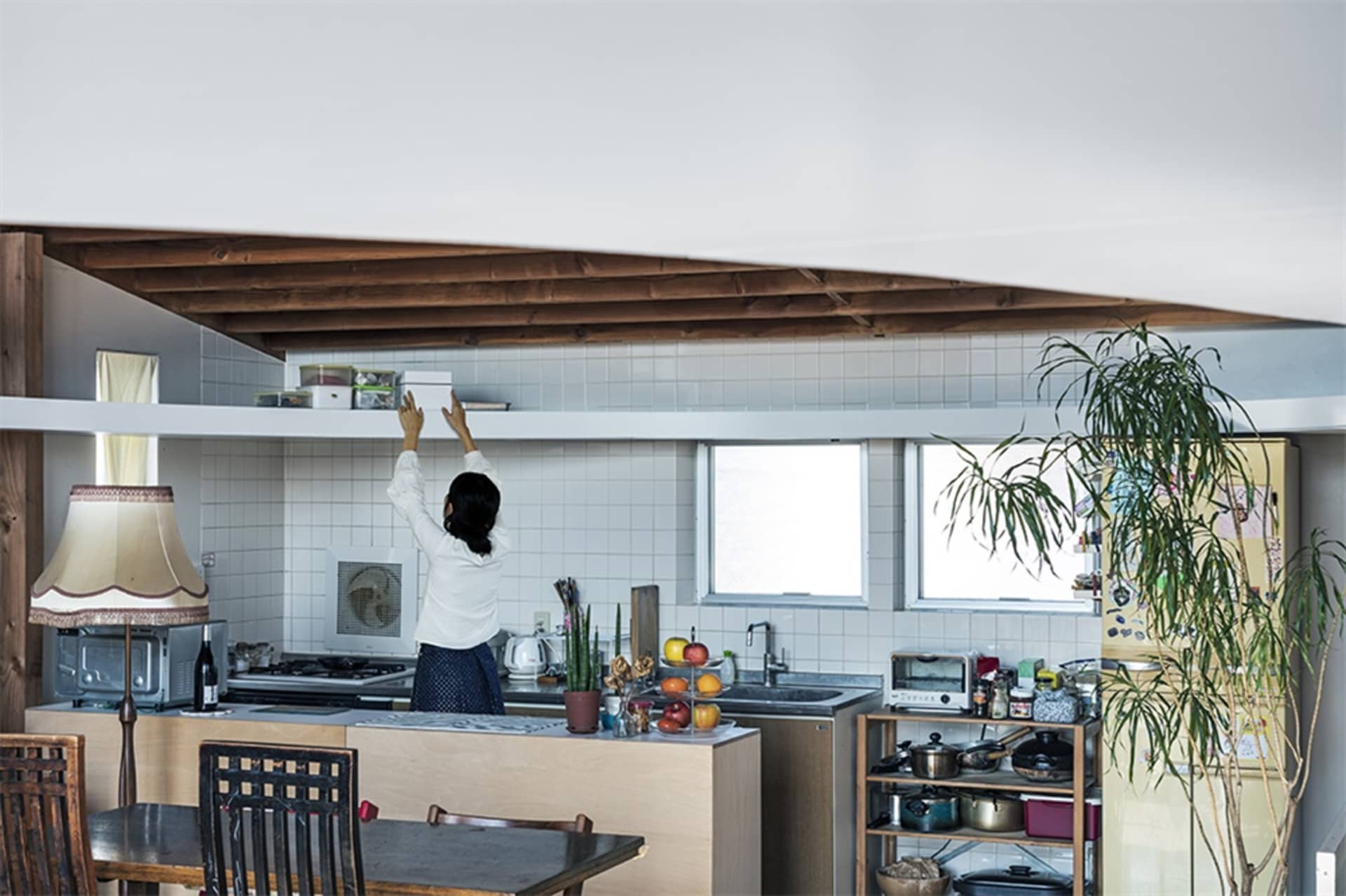 Modern kitchen with wooden shelves and glass countertops displaying assorted ingredients and containers, featuring a white wa