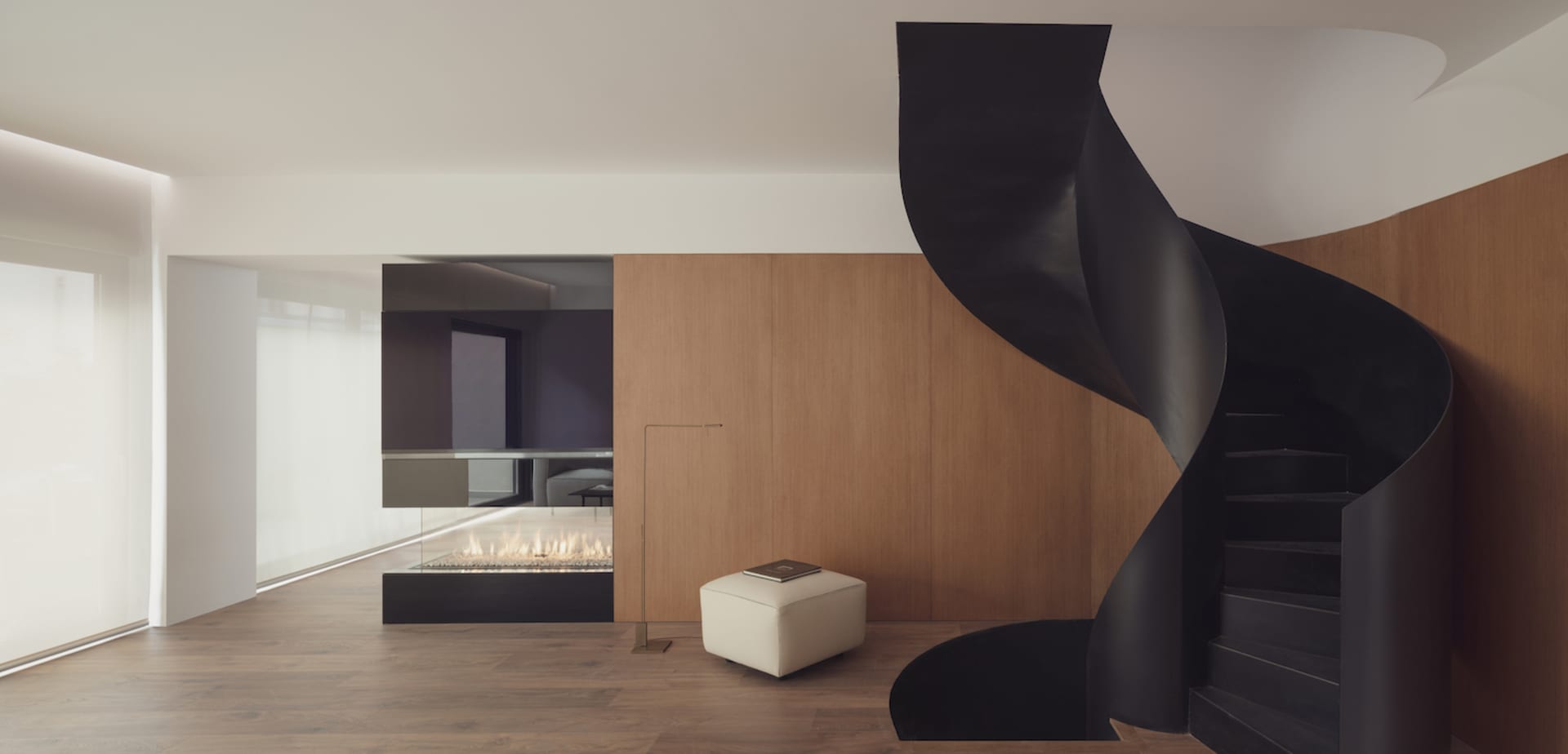 Modern residential interior featuring a spiral staircase with black metal spiral and wooden steps.