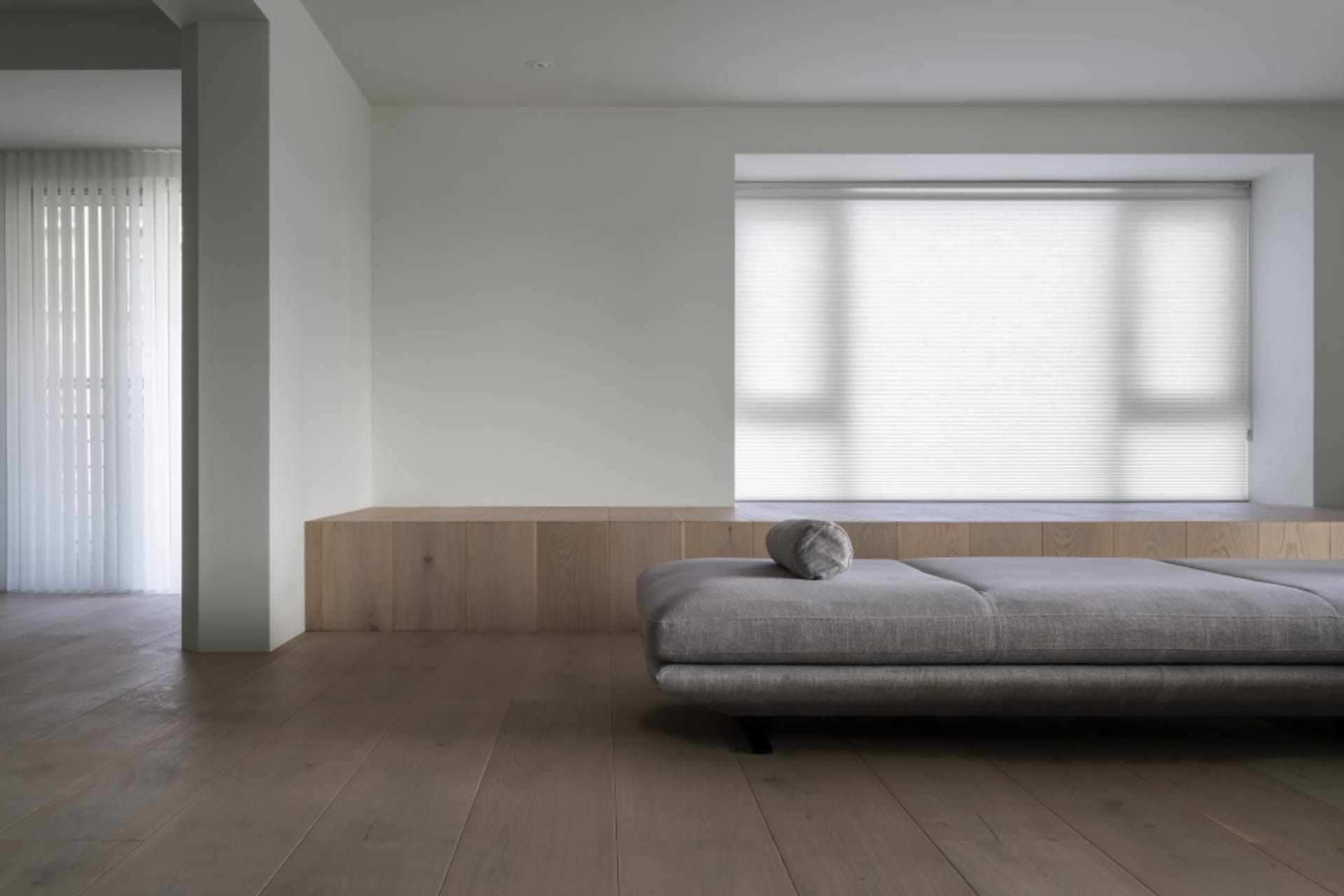 A minimalist living room featuring wood furniture and light-colored fabric.