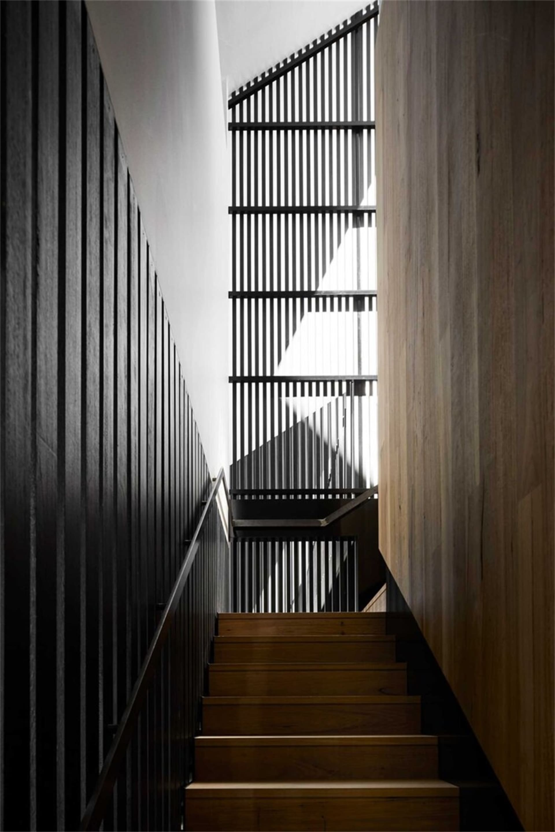 Interior staircase with wooden steps and railings, showcasing modern architectural design.