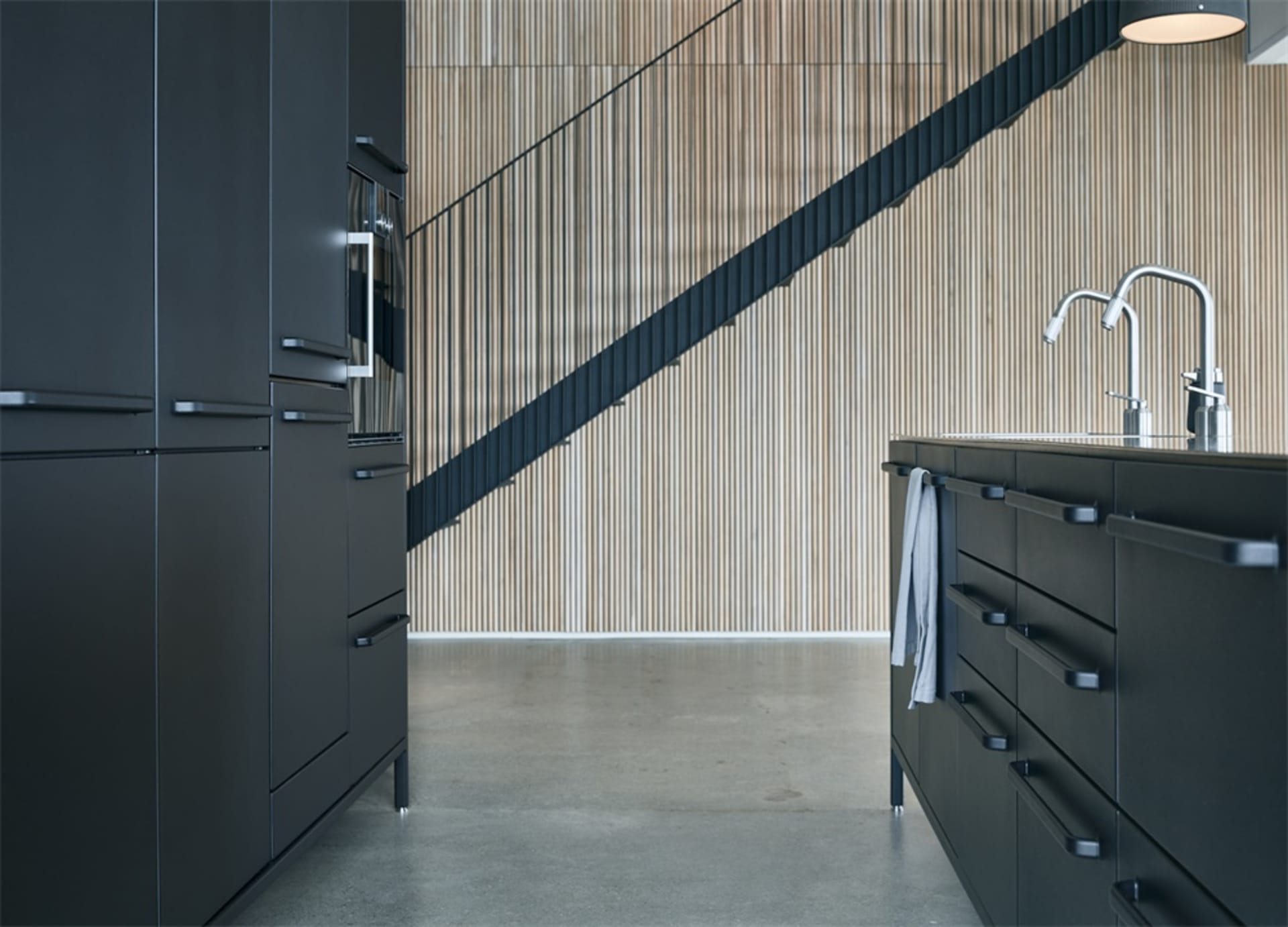 Modern, minimalist kitchen with black cabinets and a wooden backsplash.