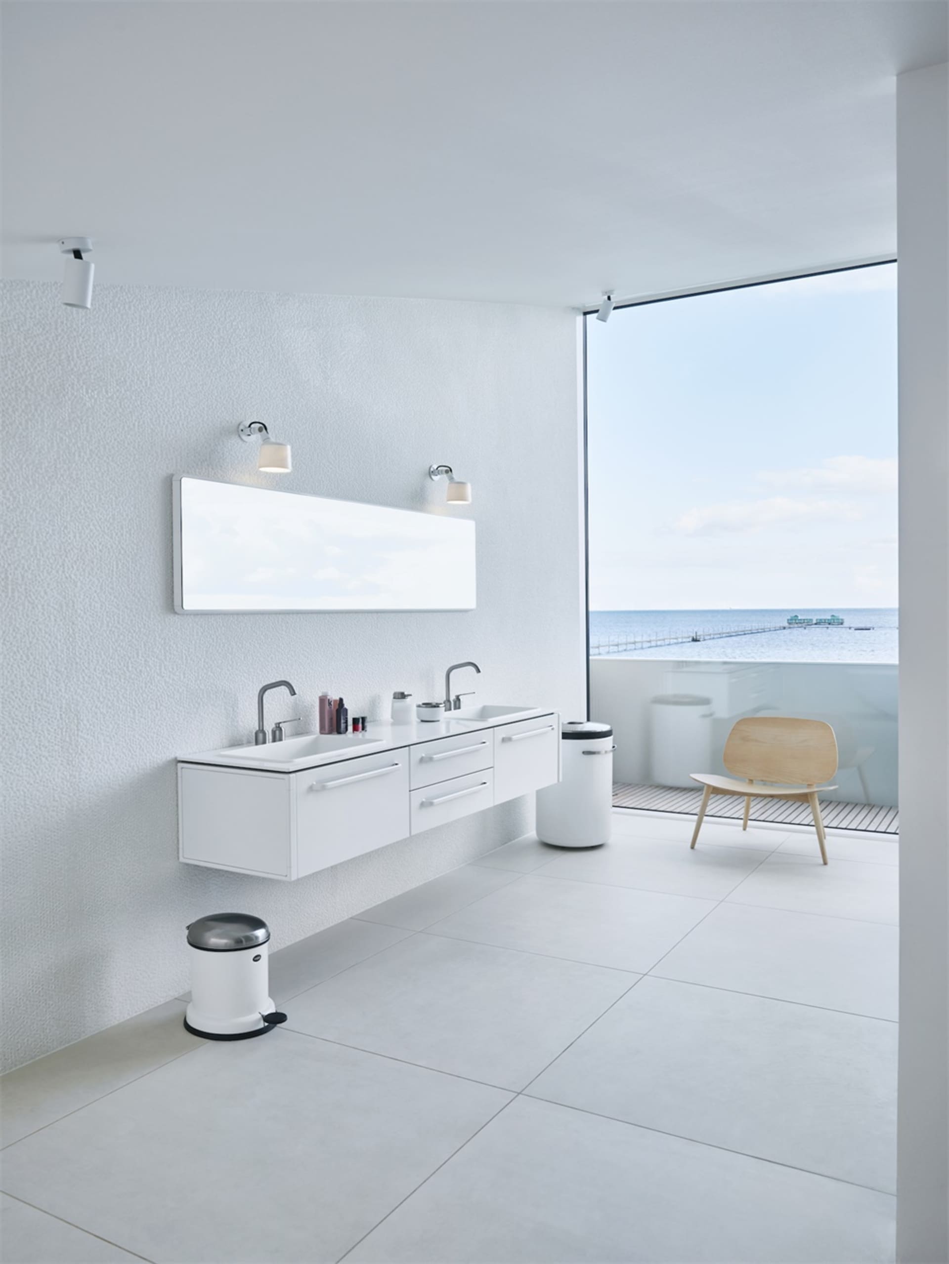 Modern minimalist white bathroom with a view of the ocean.