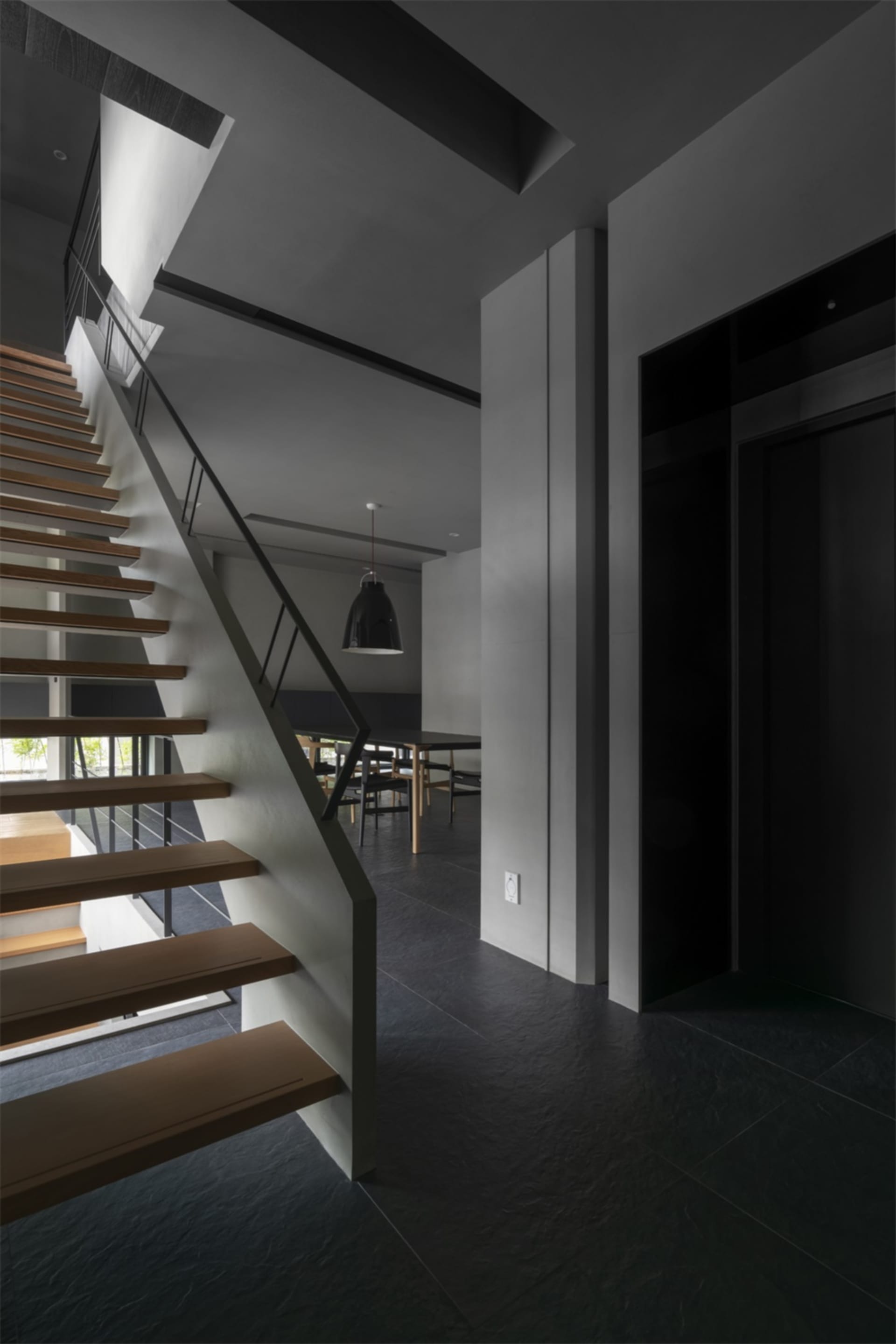 Modern entrance area with wooden stairs, concrete floor, and metal railing.