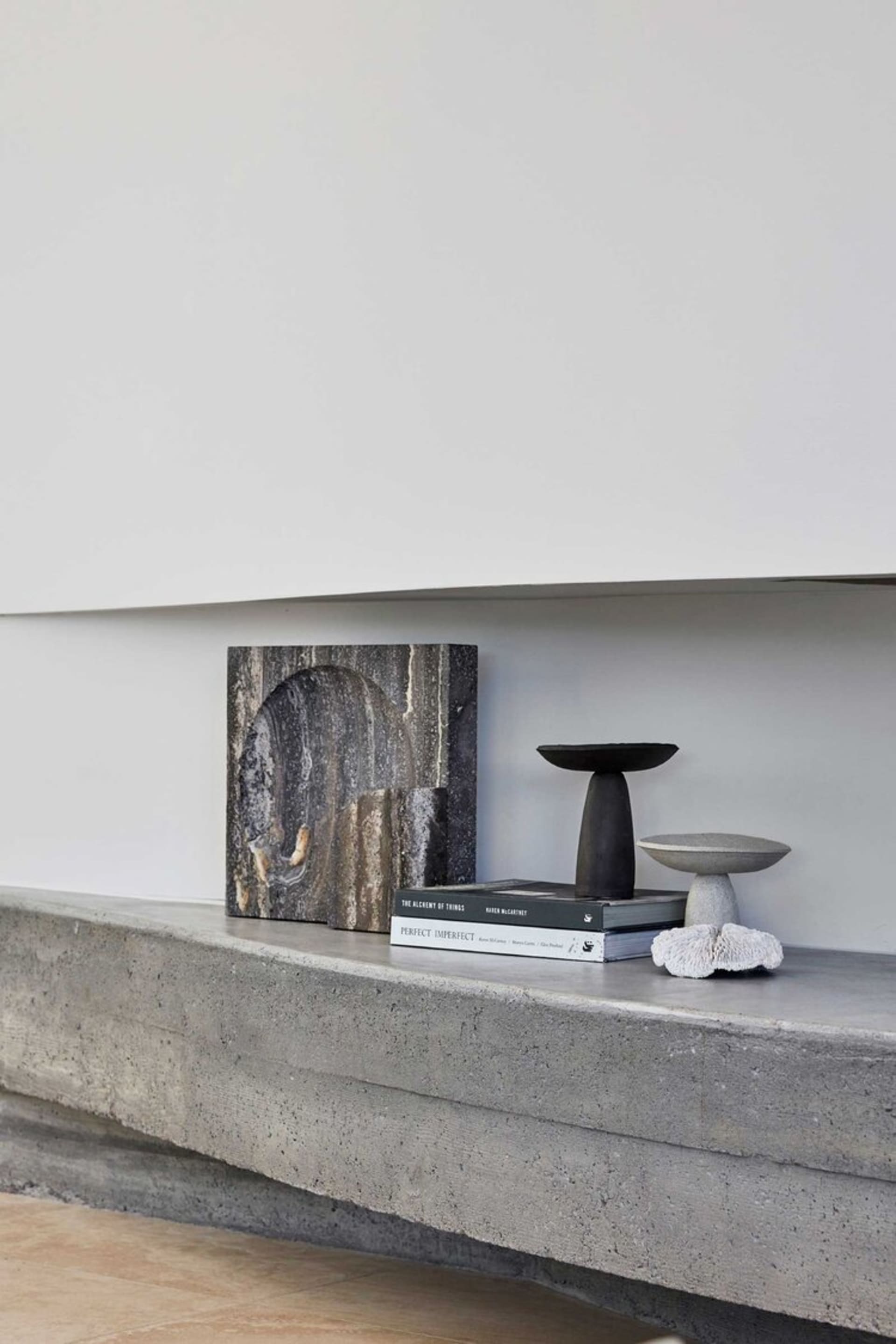 A minimalist shelf made of concrete with decorative objects on it.