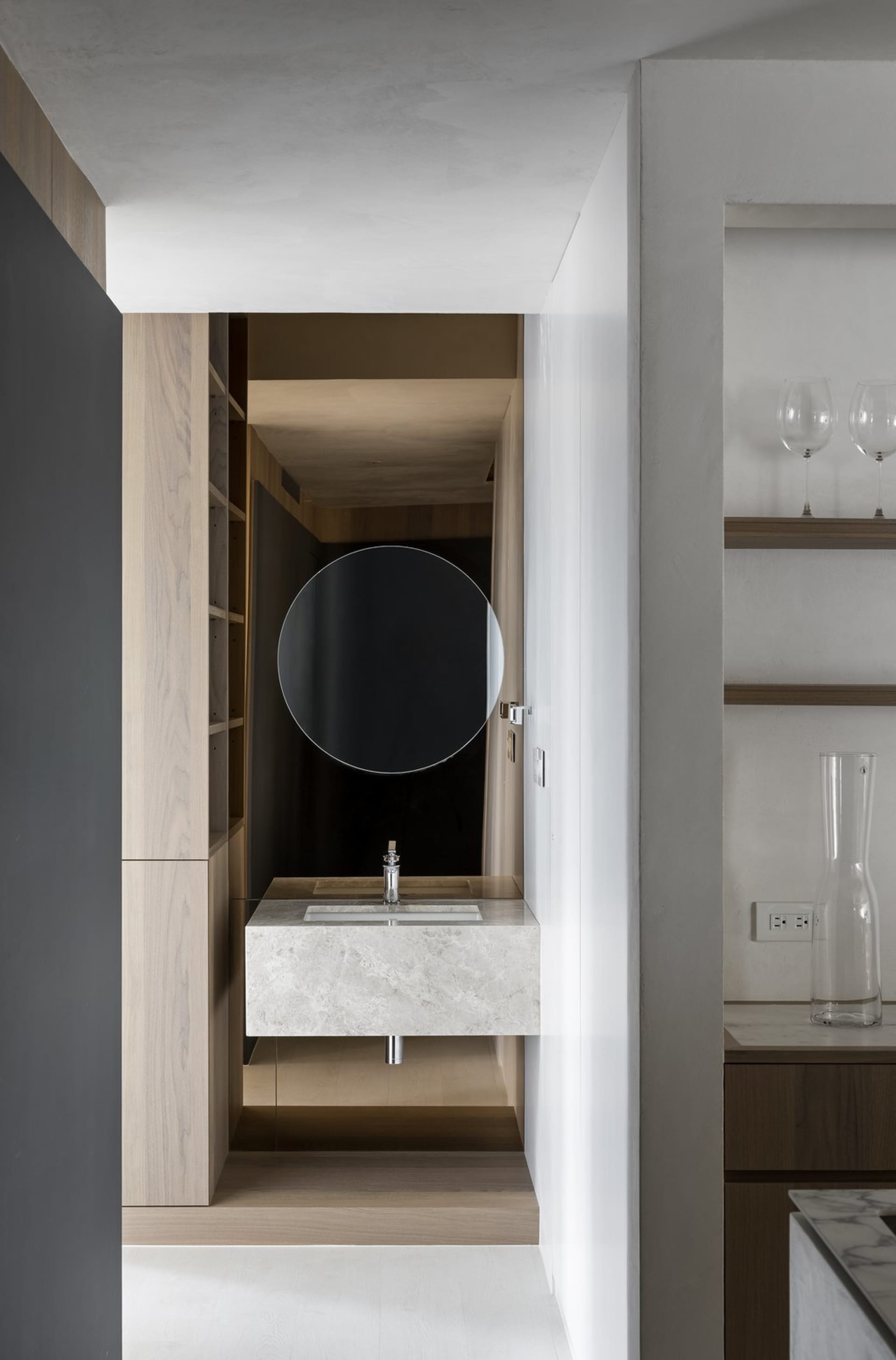 Modern minimalist bathroom featuring a white marble countertop with a circular mirror above it.