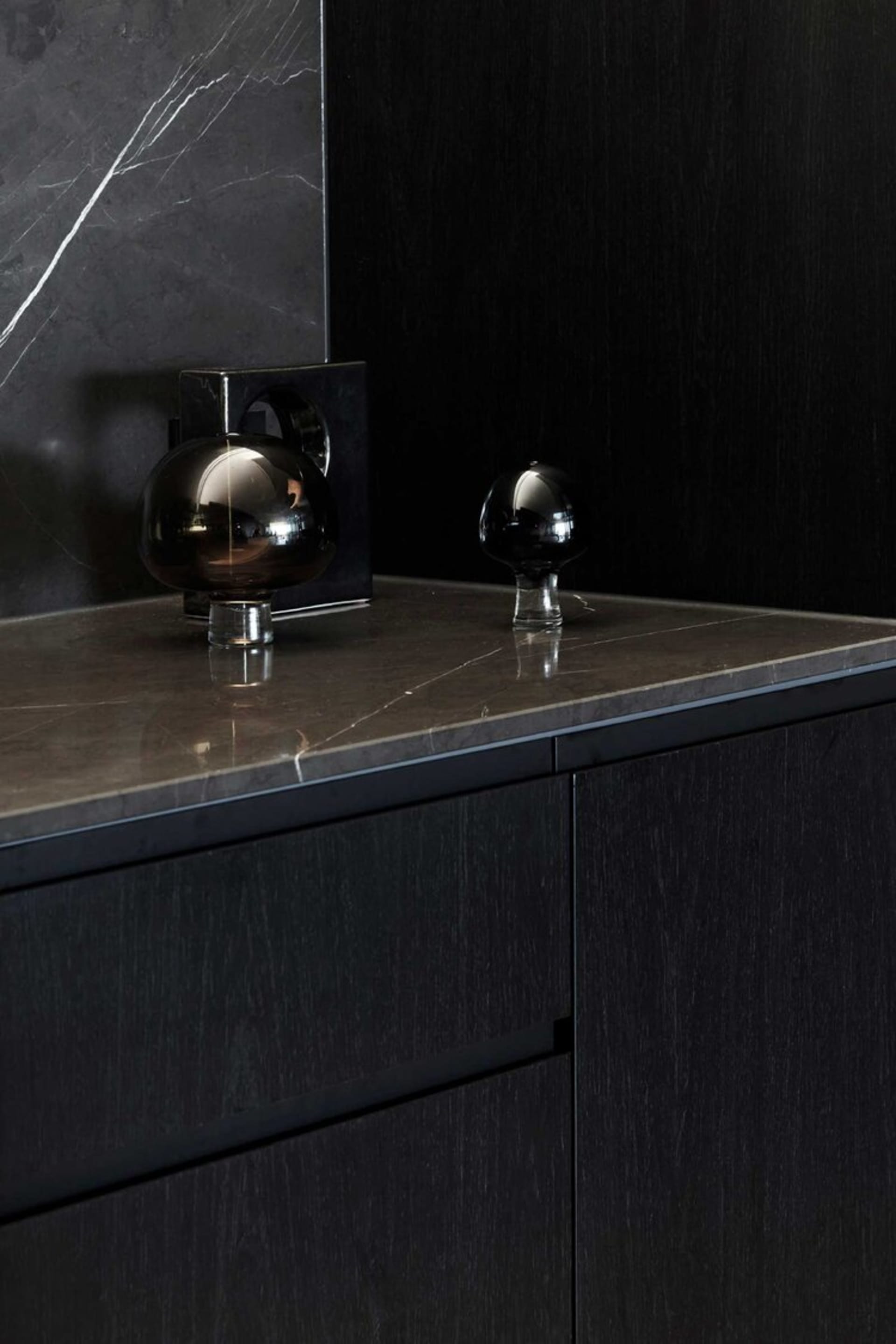 Modern kitchen with black cabinets and marble countertop.