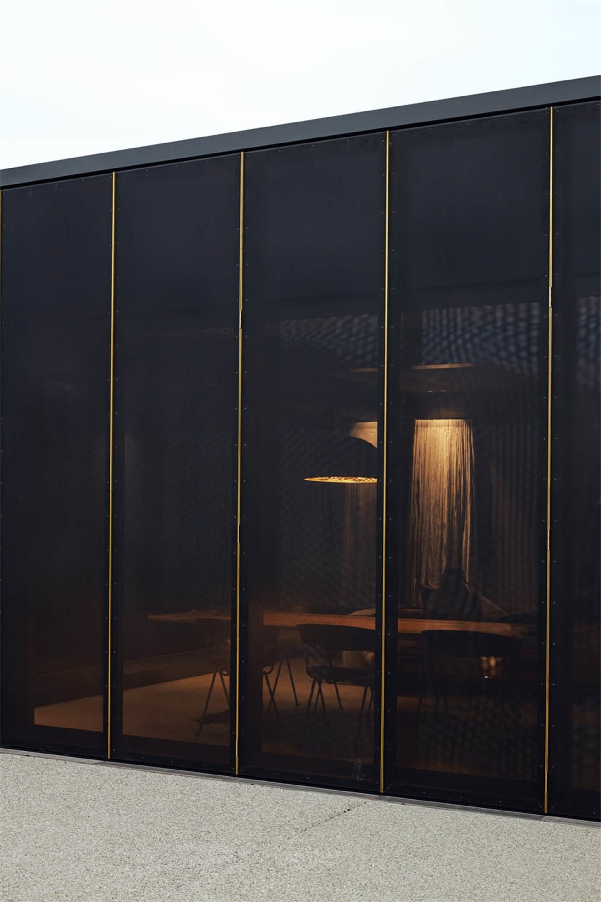 A modern industrial office with black metallic screens and warm lighting.