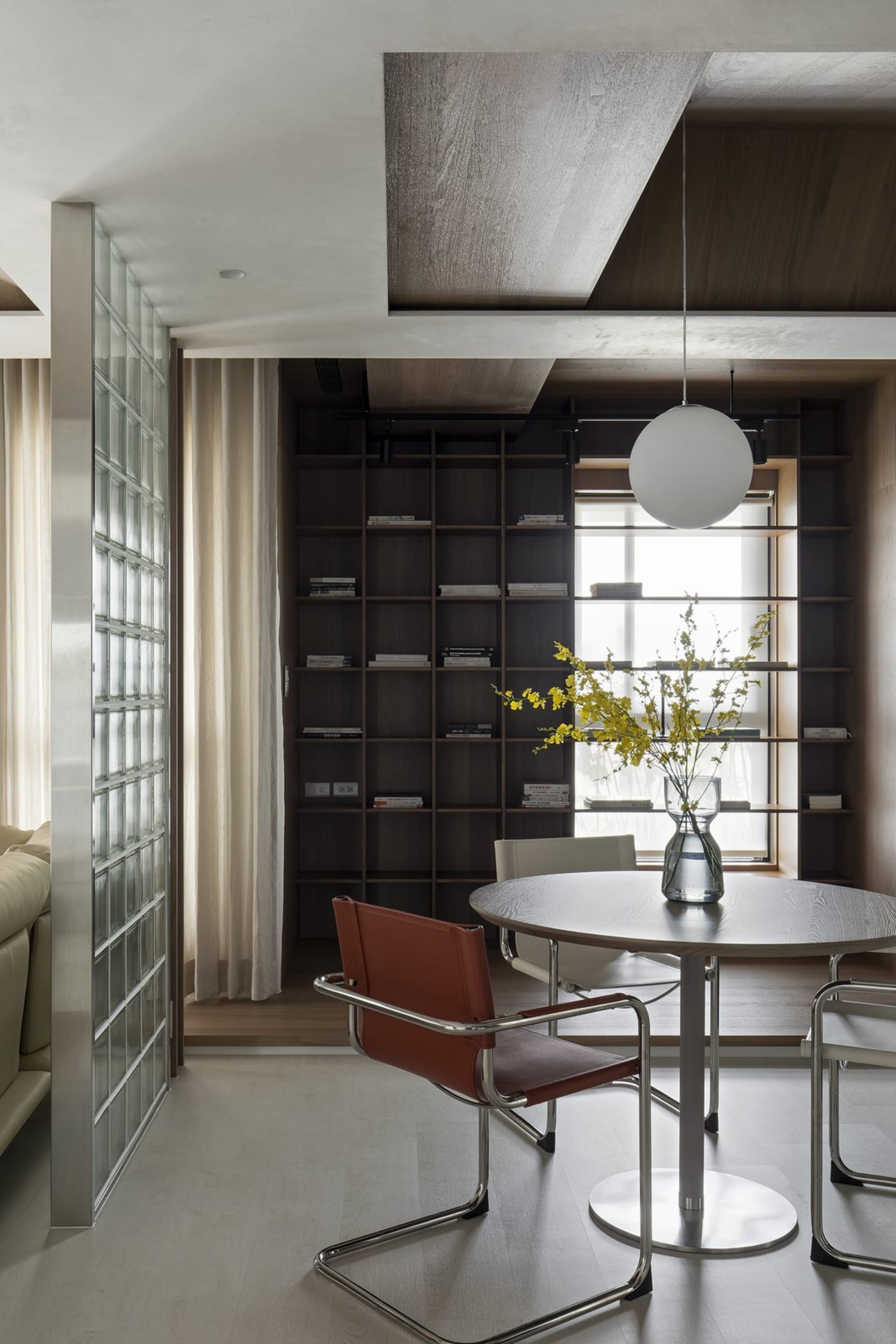 Modern interior featuring a library-office with wooden shelves, glass walls, and metal accents.