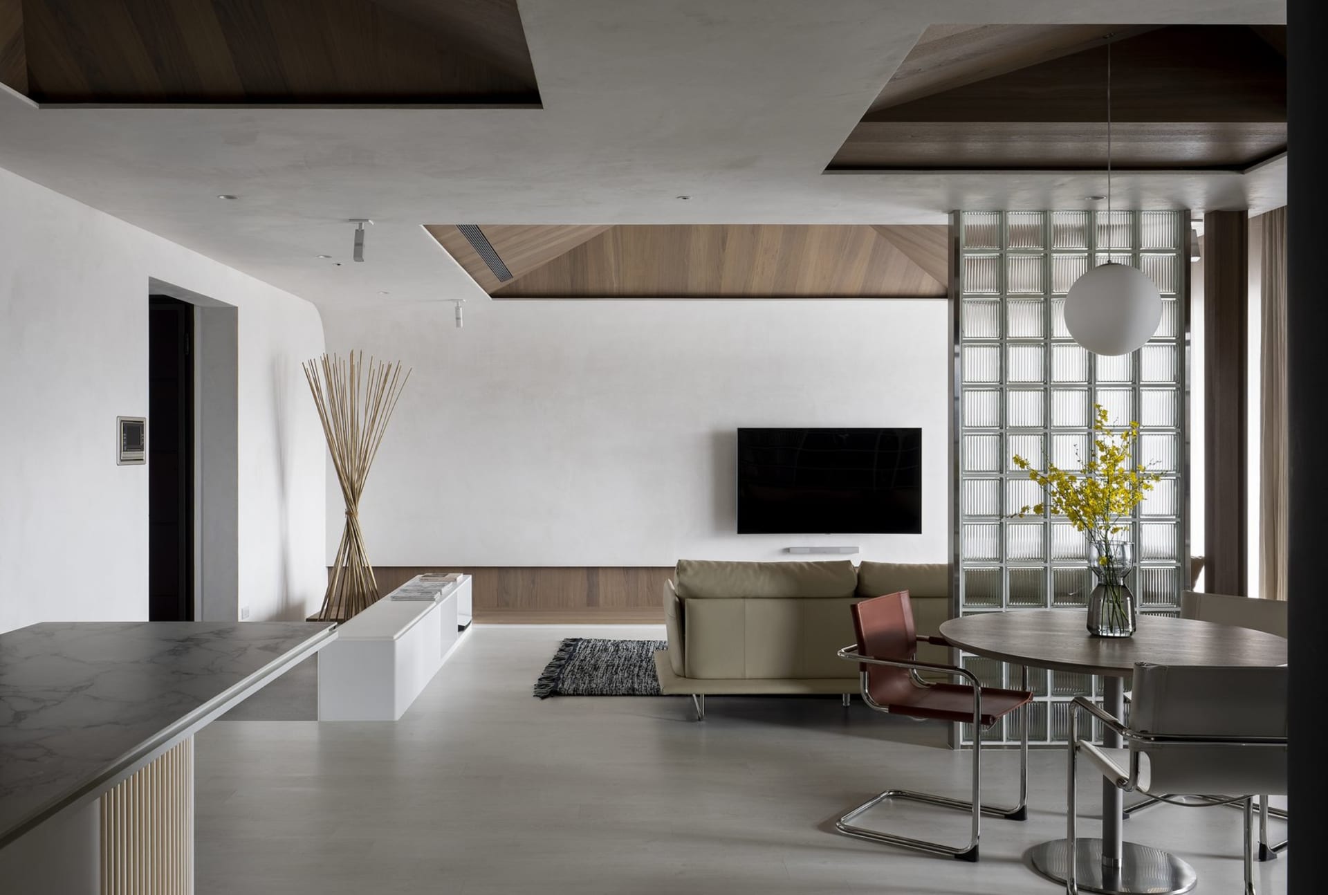 A modern minimalist living room with white walls and wooden elements, featuring a white sofa, wooden coffee table, and minima