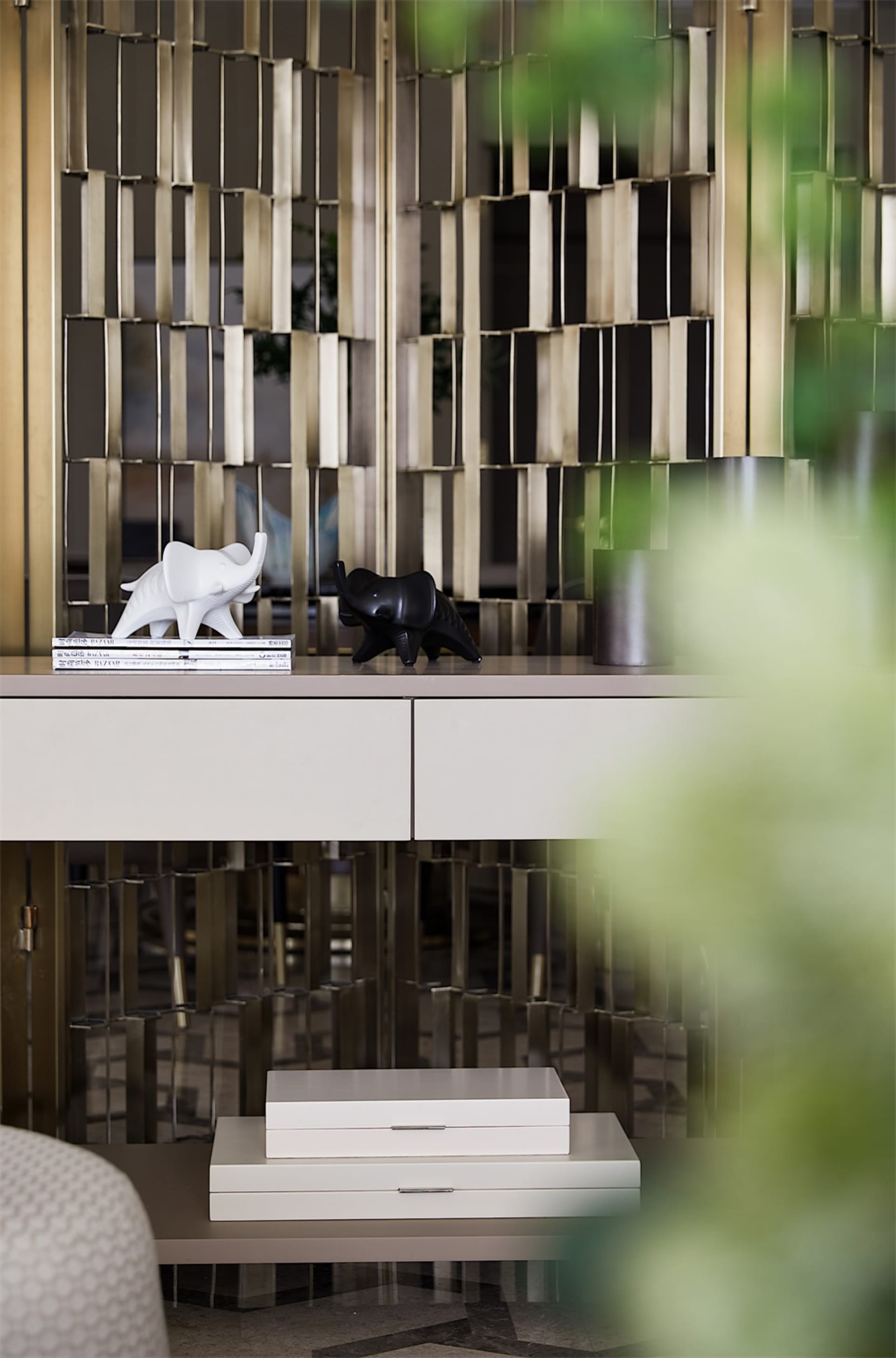 Two ceramic elephant sculptures, one white and one black, placed on top of a white surface with a white ceramic drawer unit.