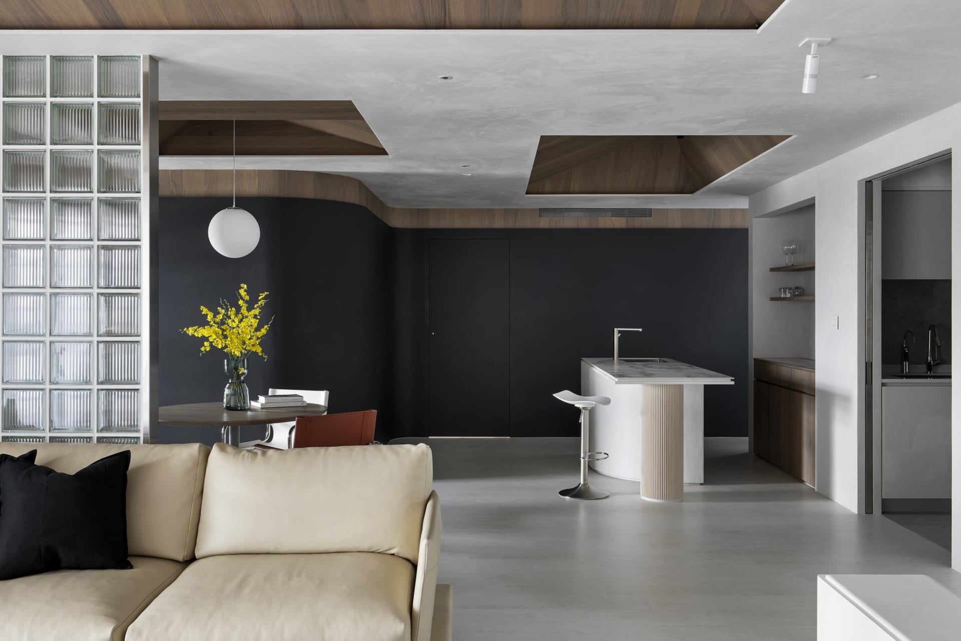 A modern living room with a glass window, wooden furniture, and a concrete floor.