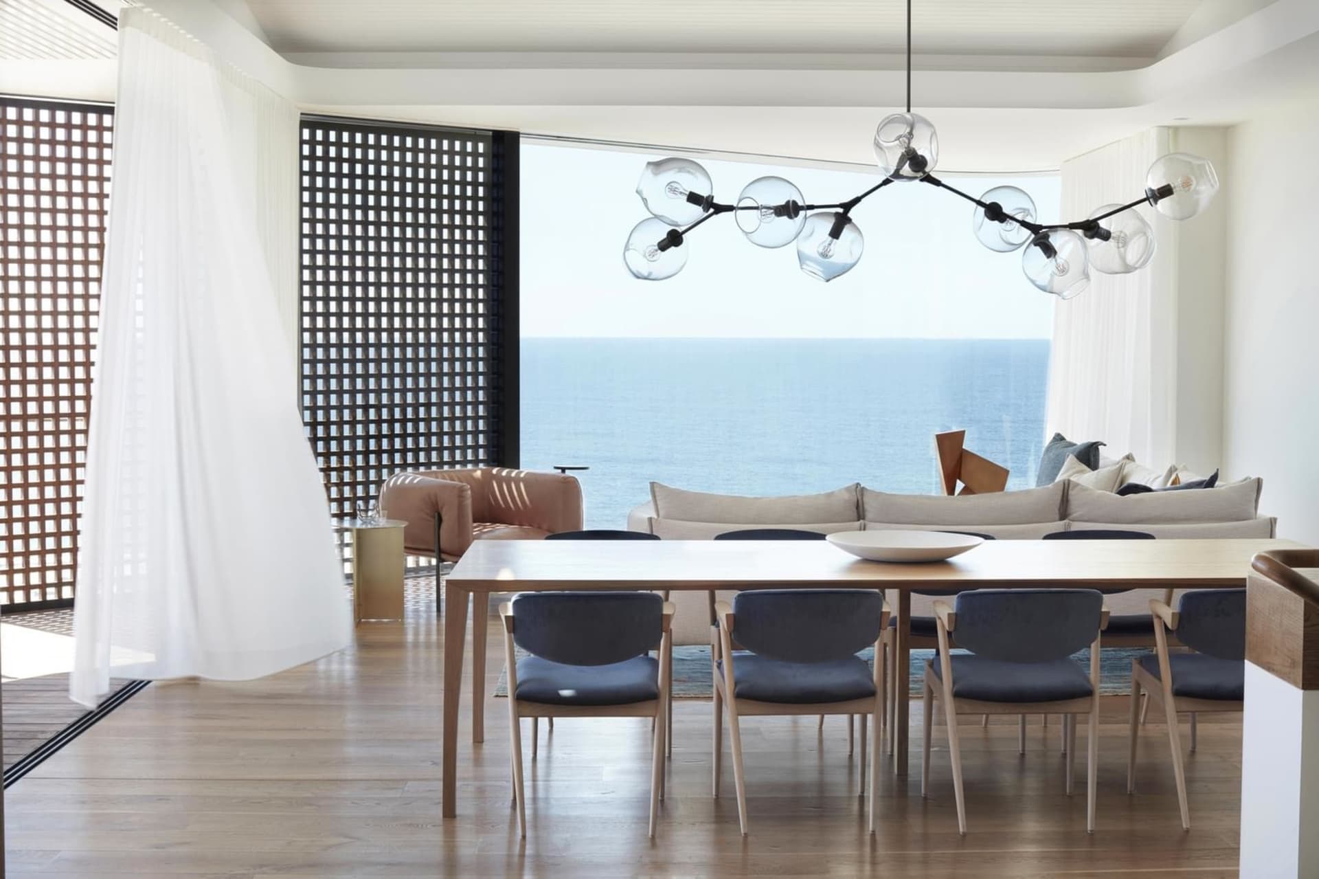 Modern, minimalist living room featuring a spacious open concept layout, with a large dining table and comfortable seating ar