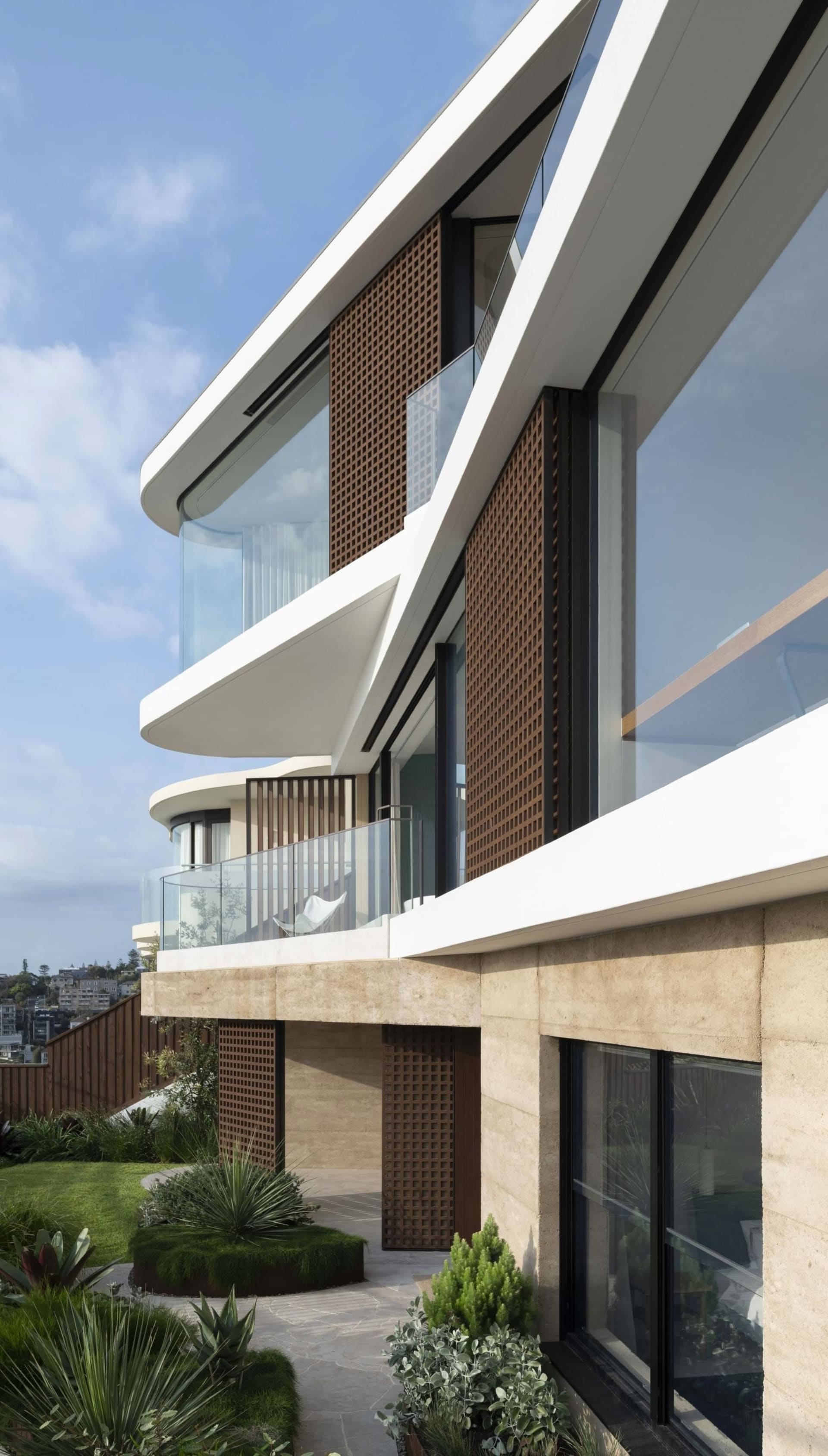 Modern exterior of a penthouse with glass walls, stone cladding, and timber accents.