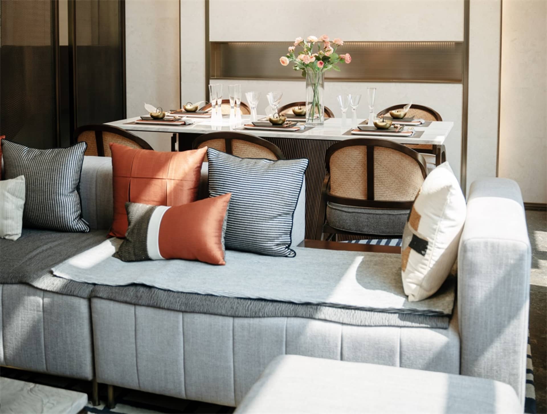 A modern living room with a grey sectional sofa adorned with patterned and solid-colored throw pillows and a plush blanket. T
