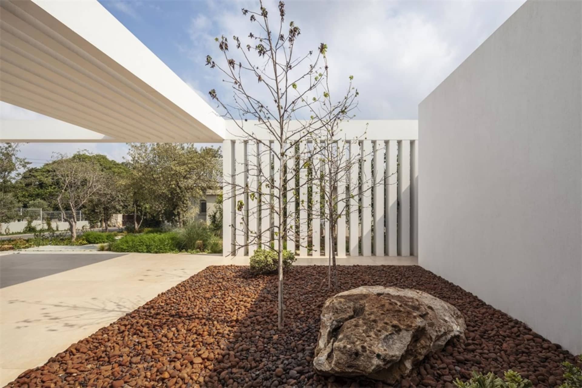 A modern minimalist exterior space featuring concrete surfaces and rockery landscaping.