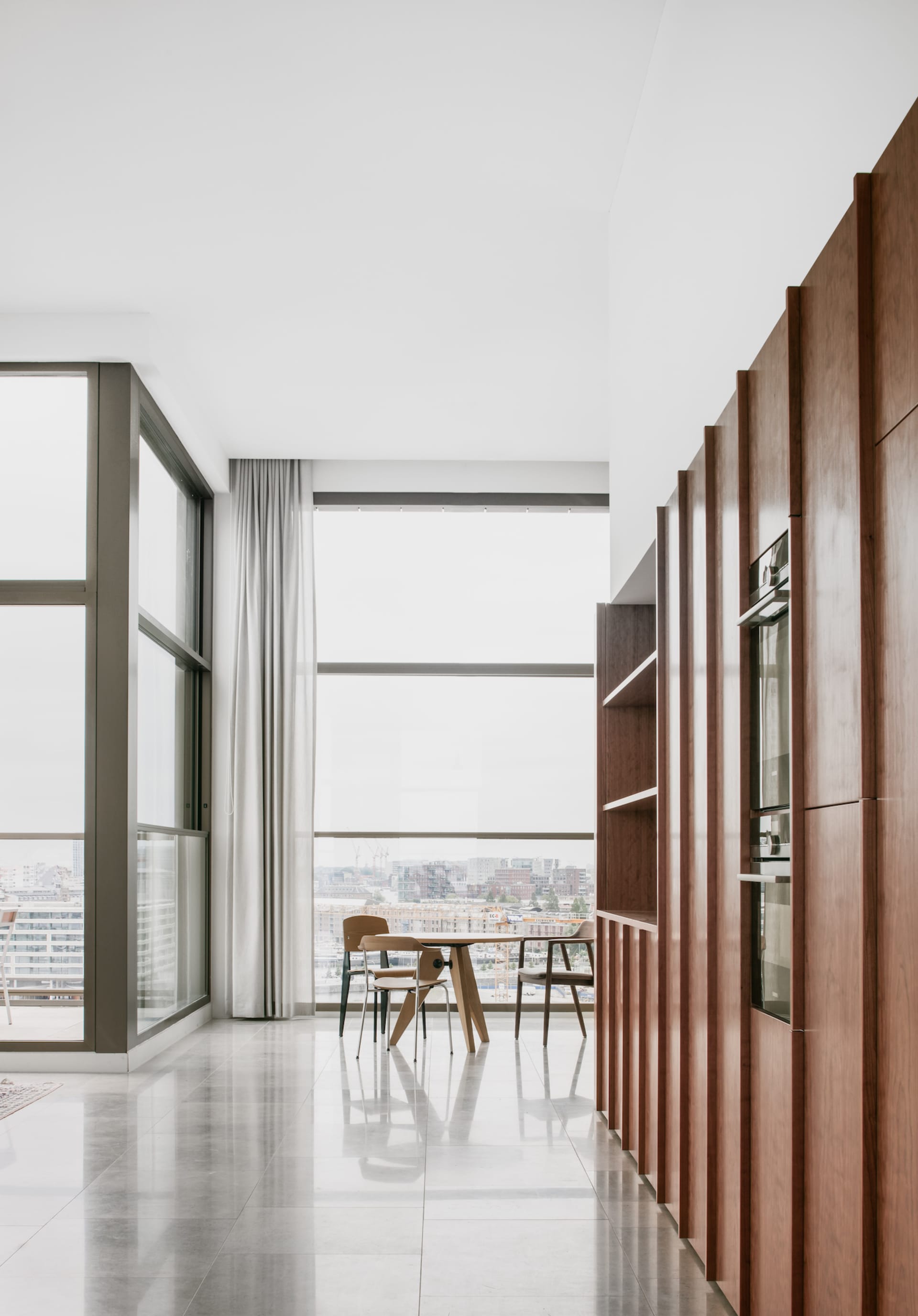 A modern office space with concrete and glass walls and a kitchen area.