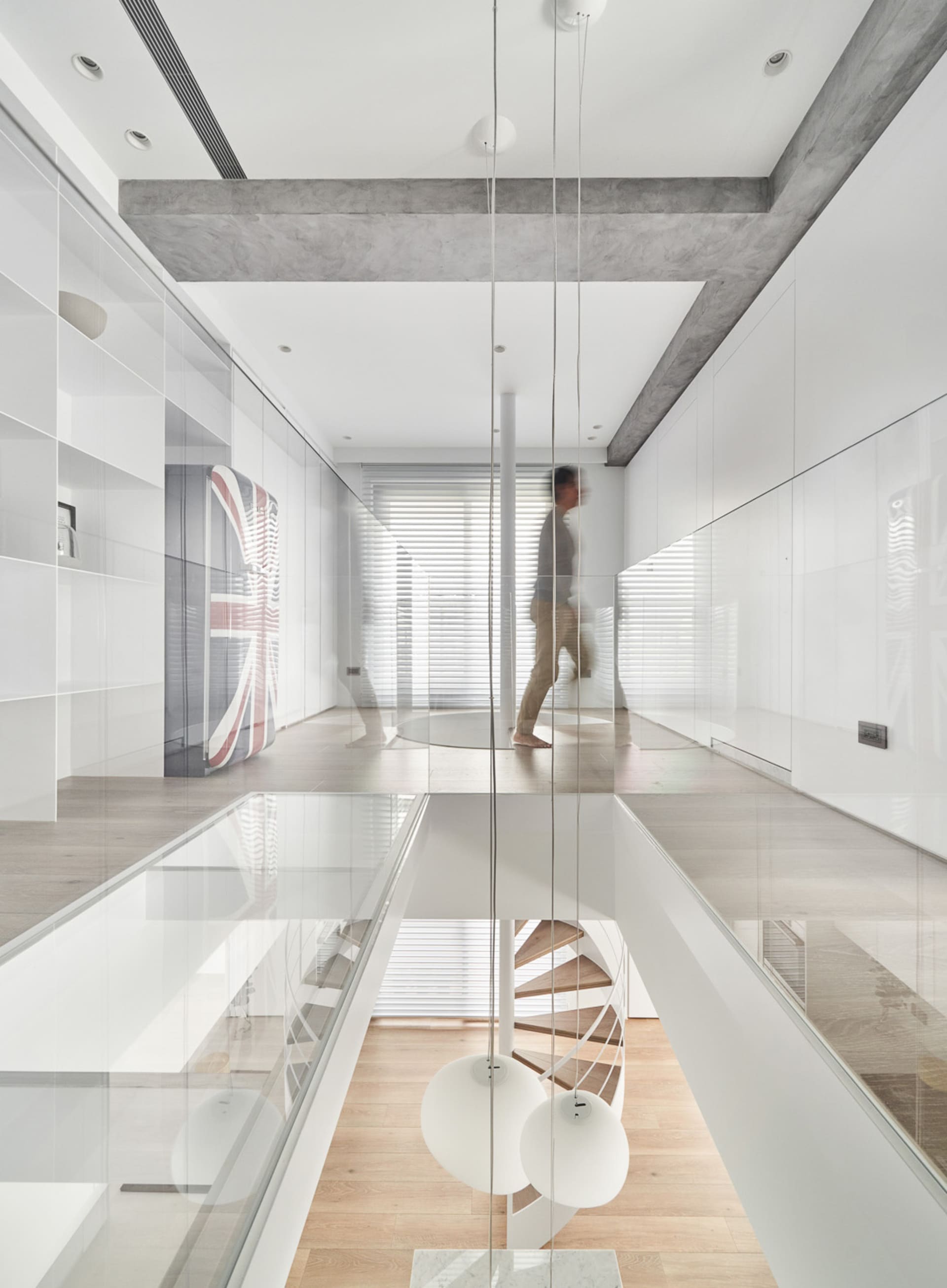 A minimalist interior space featuring white walls, concrete columns, and wooden flooring.