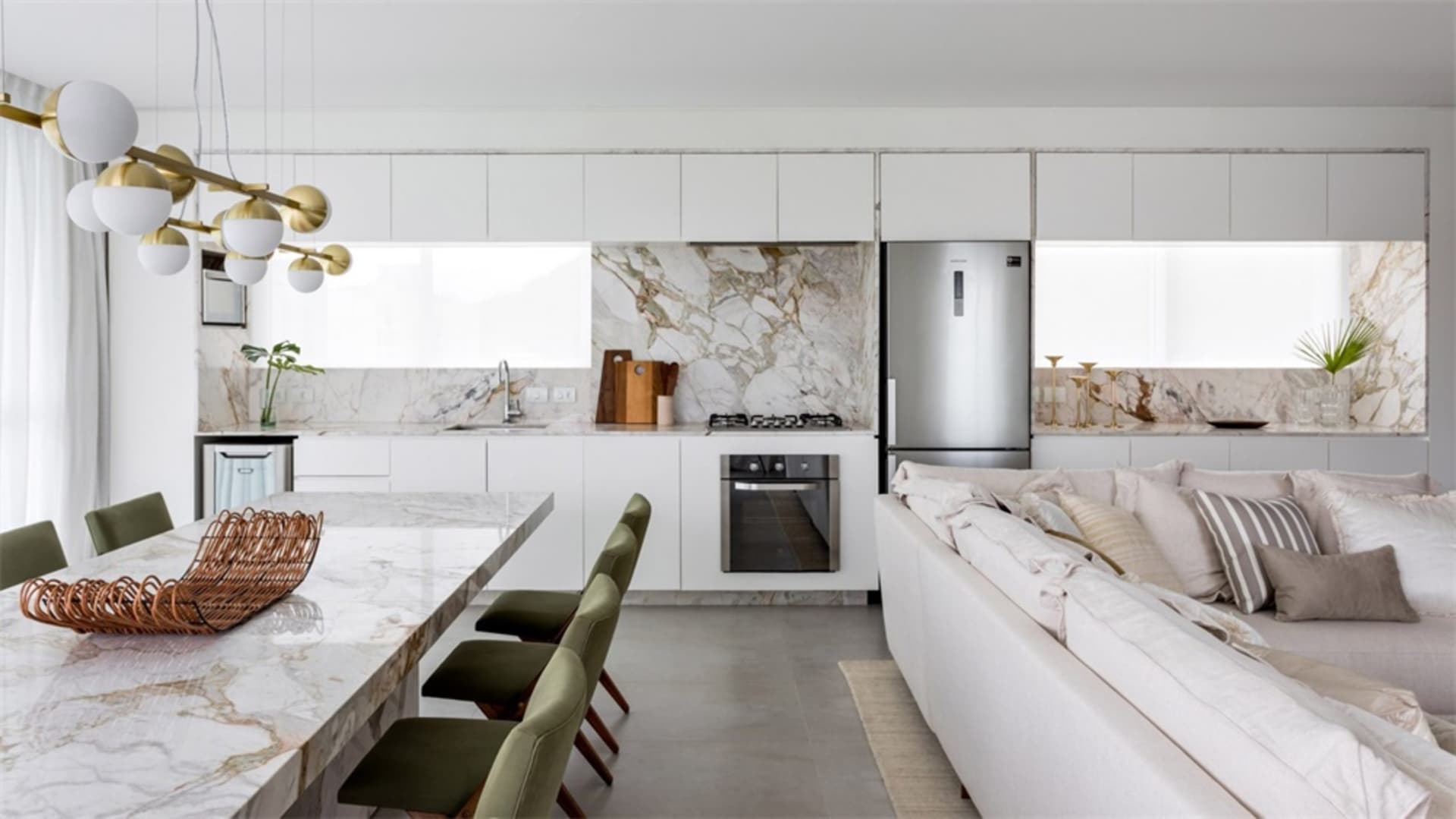 A minimalist kitchen with marble countertops and white cabinets.