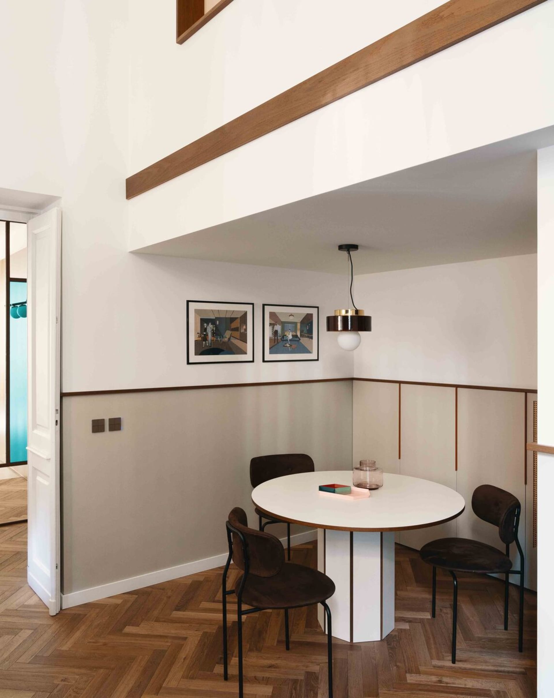 A modern dining room with a round table, chairs, and artwork on the wall.