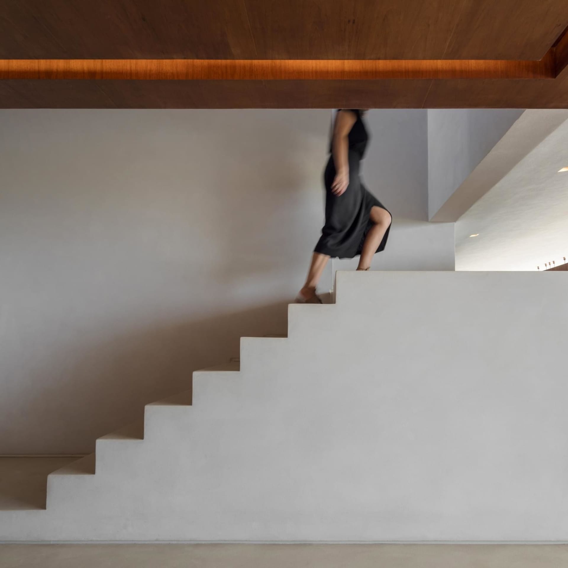 A modern, minimalist staircase made of concrete with a wooden ceiling.