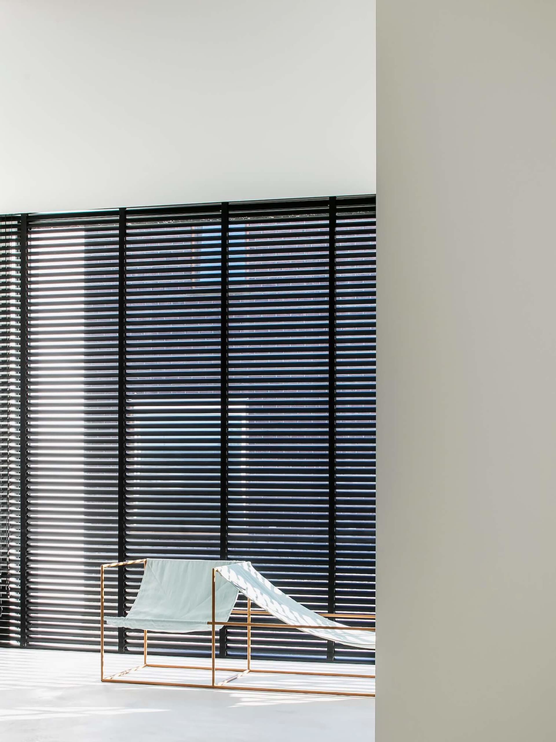 Modern interior featuring metallic blinds, minimalist furniture, and geometric shapes.