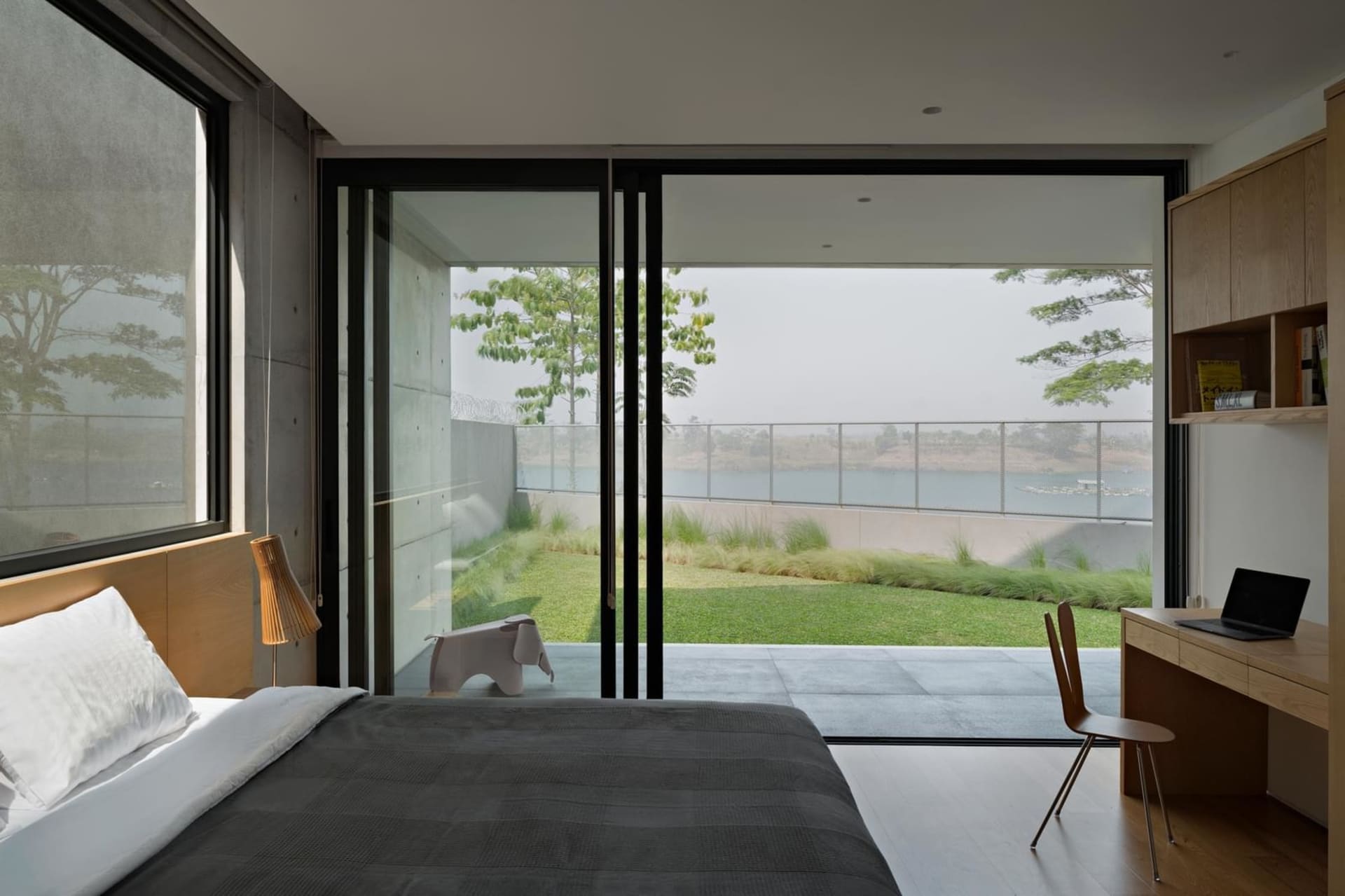 A minimalist bedroom featuring a bed with a wooden headboard and a glass coffee table.