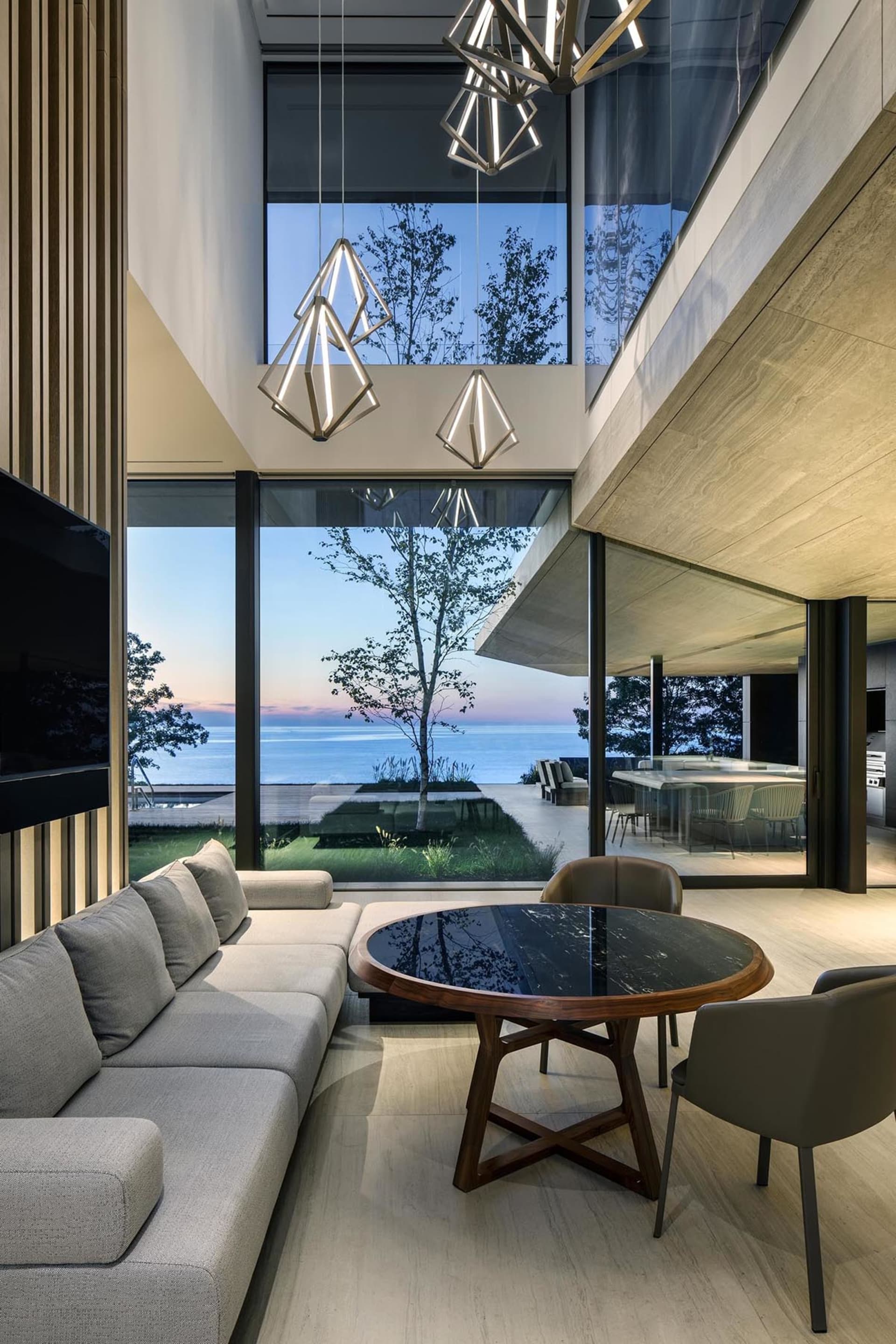 A modern living room featuring concrete and glass materials with a large window overlooking the sea.