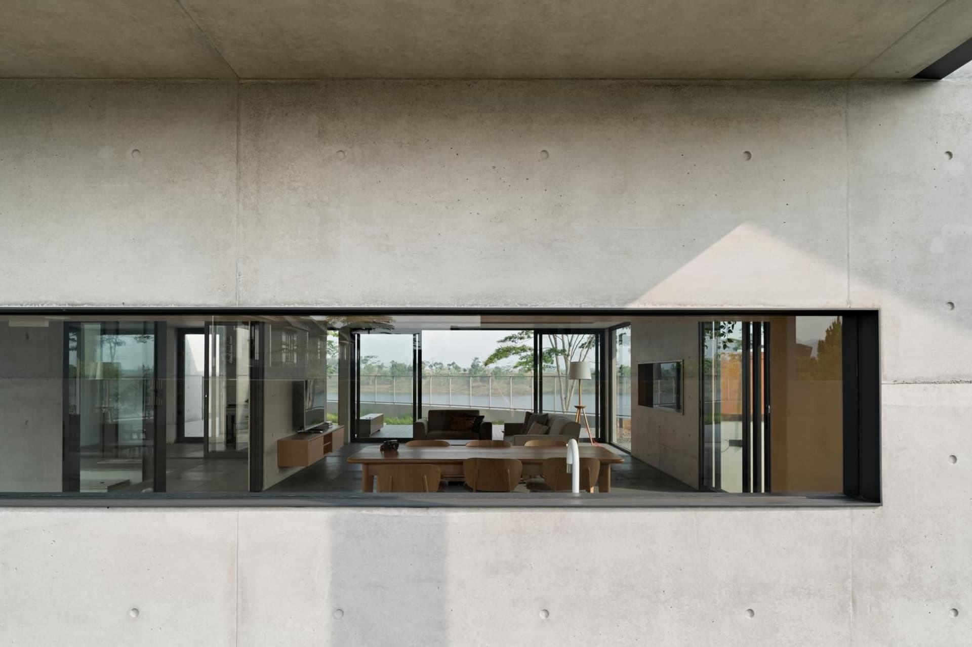 Modern living room featuring a concrete wall with a large window.