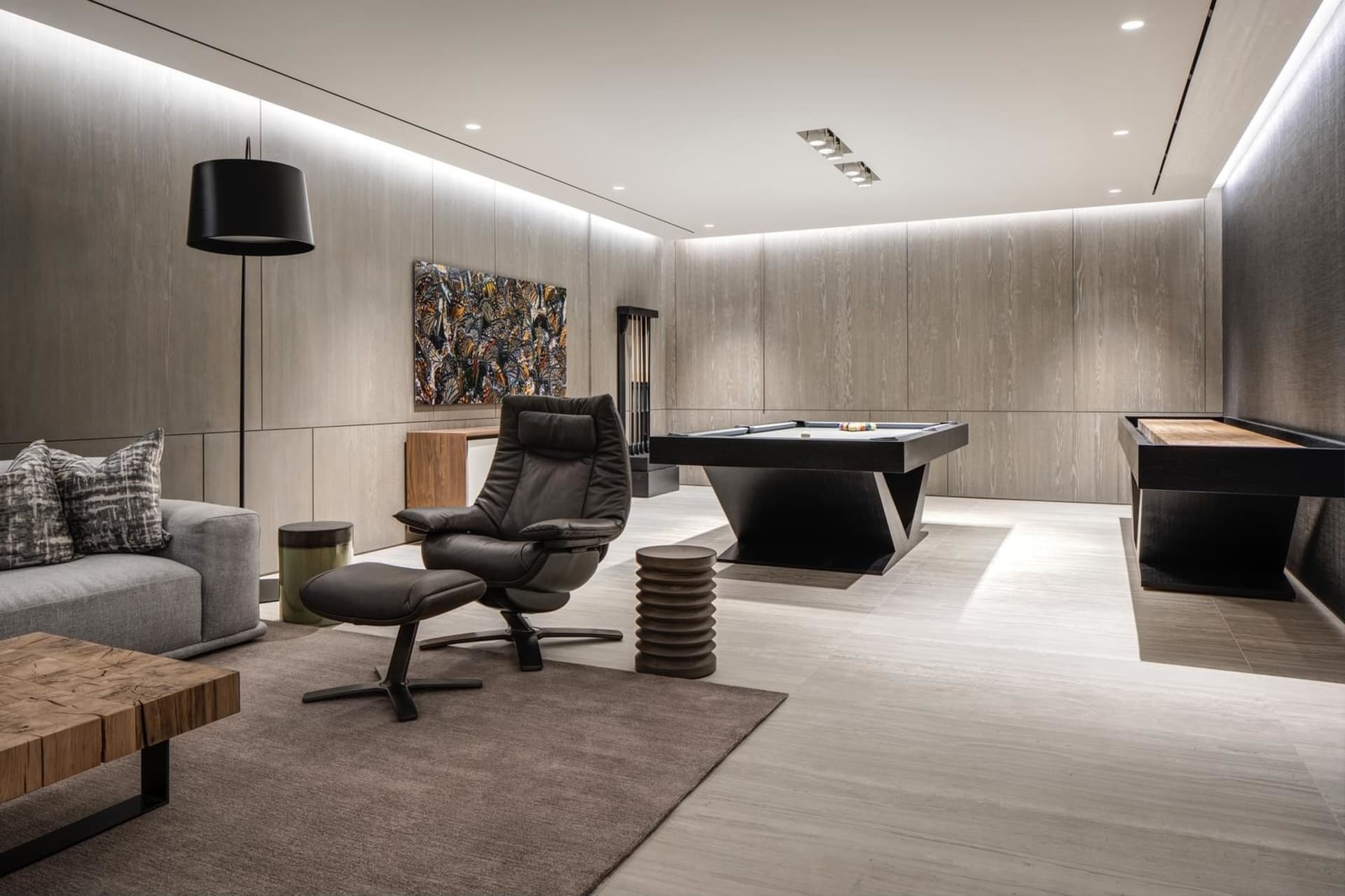 Modern living room featuring a contemporary leather recliner chair, wooden coffee table, and a sleek black pool table with bi