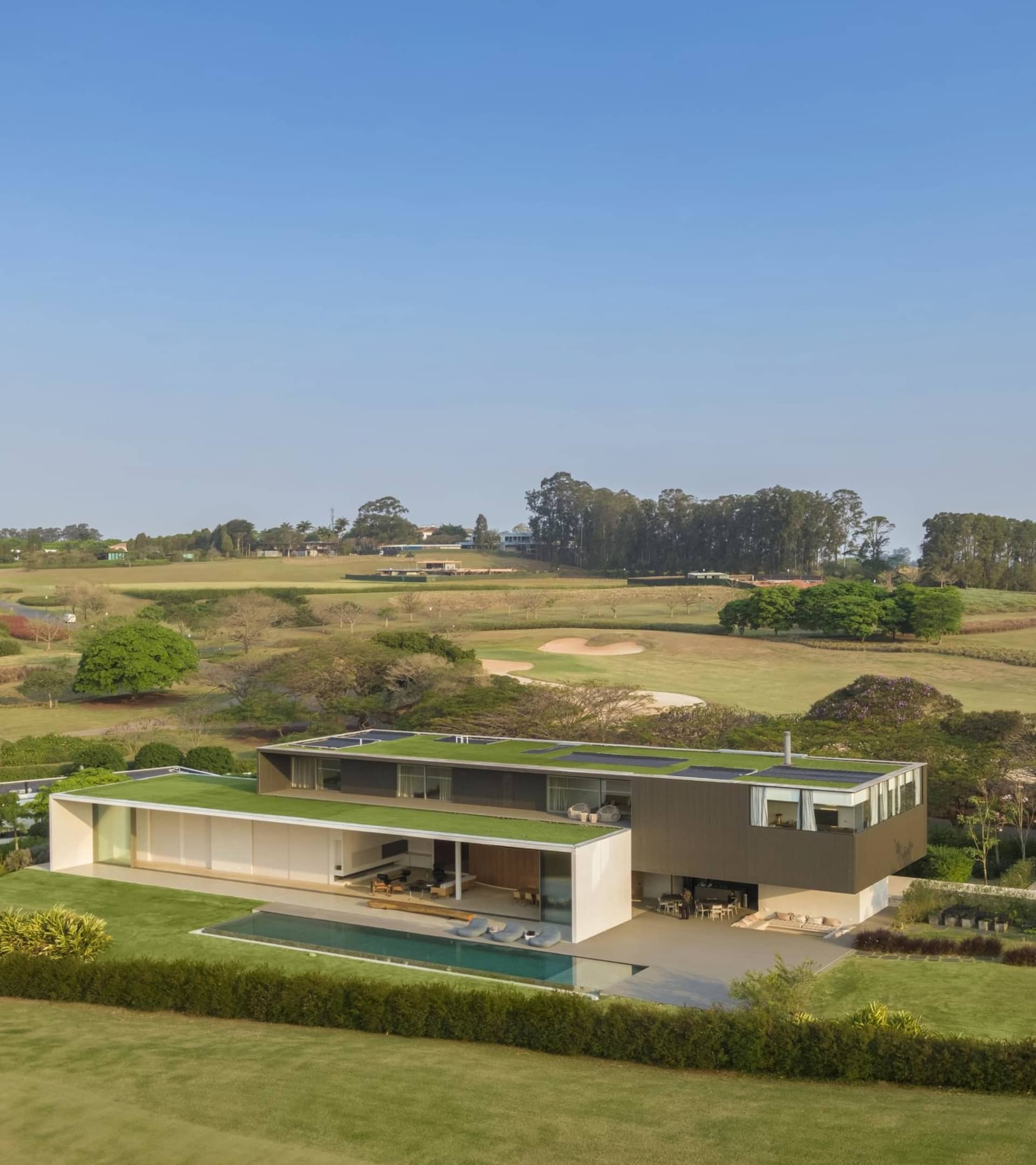 Modern residential home featuring steel and glass structure with a green rooftop.