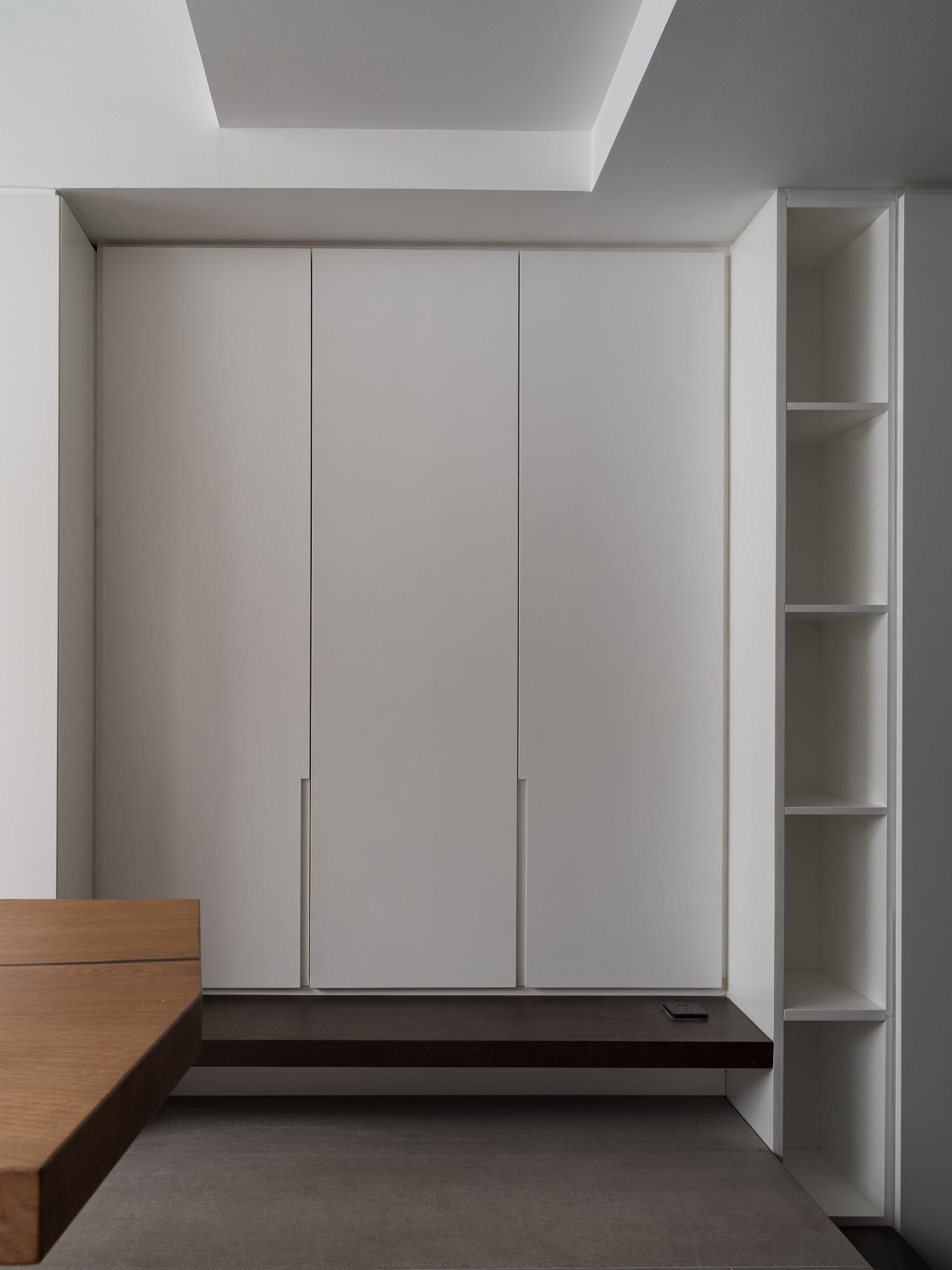A minimalist bedroom featuring white cabinets and wooden furniture.