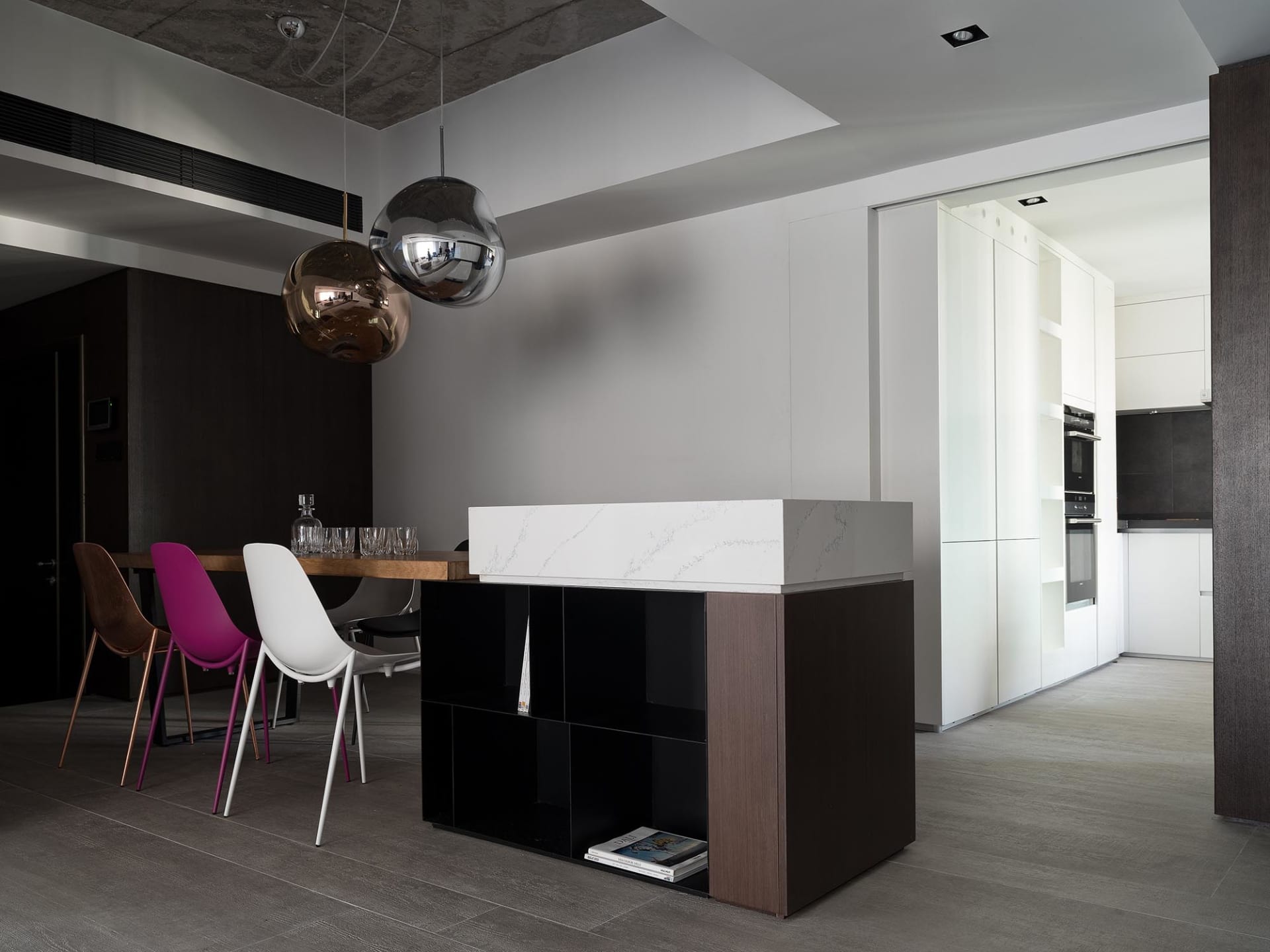 A modern dining and kitchen space featuring marble countertops and concrete finishes.