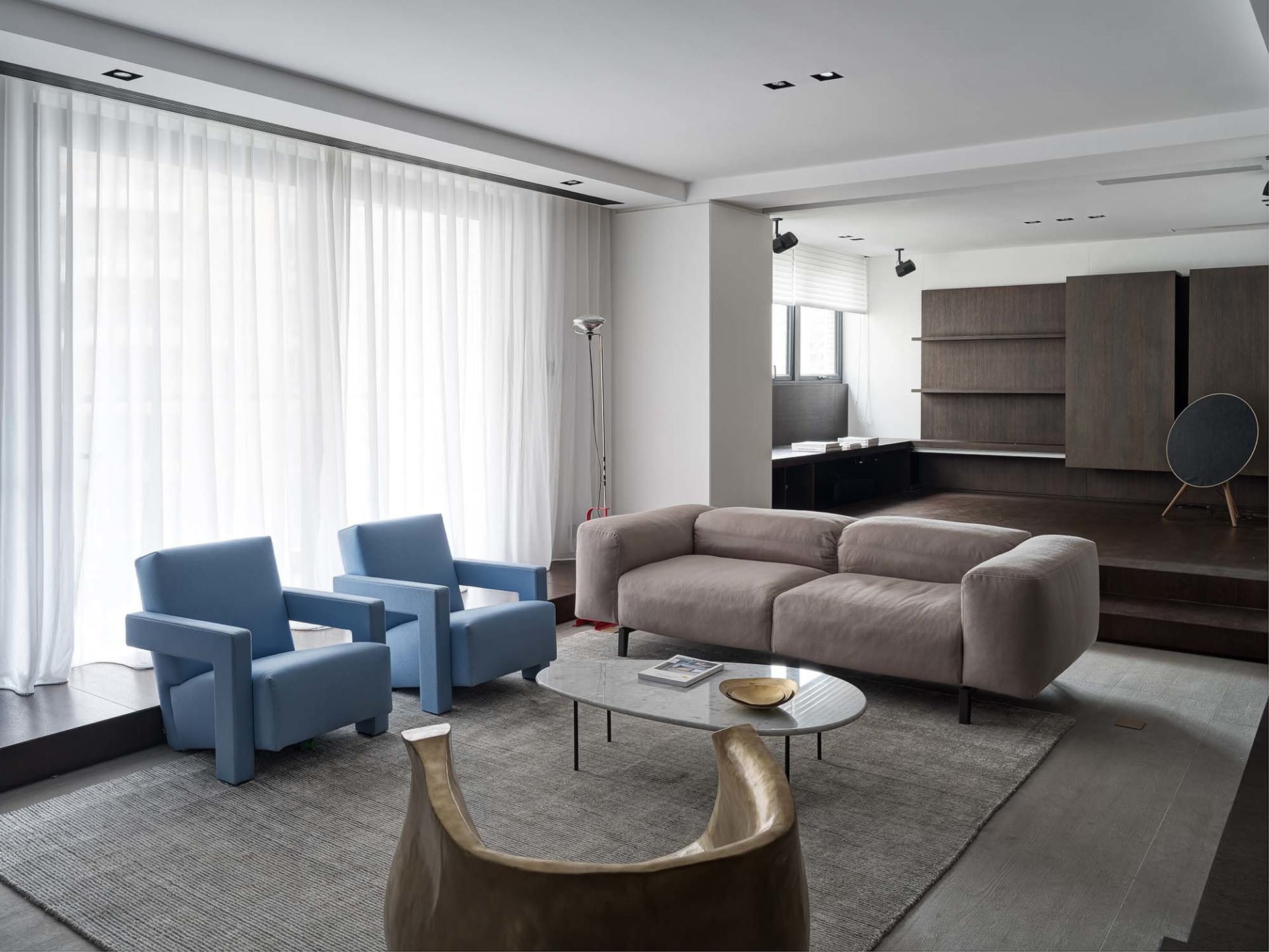 Contemporary living room with blue armchairs, gray sofa, and marble coffee table.