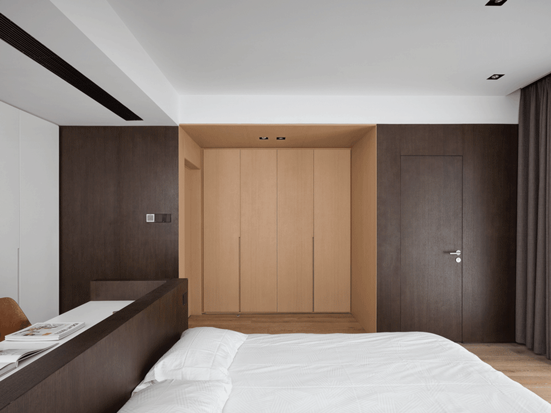 Modern minimalist bedroom featuring wood furniture, white bedding, and a large wardrobe.