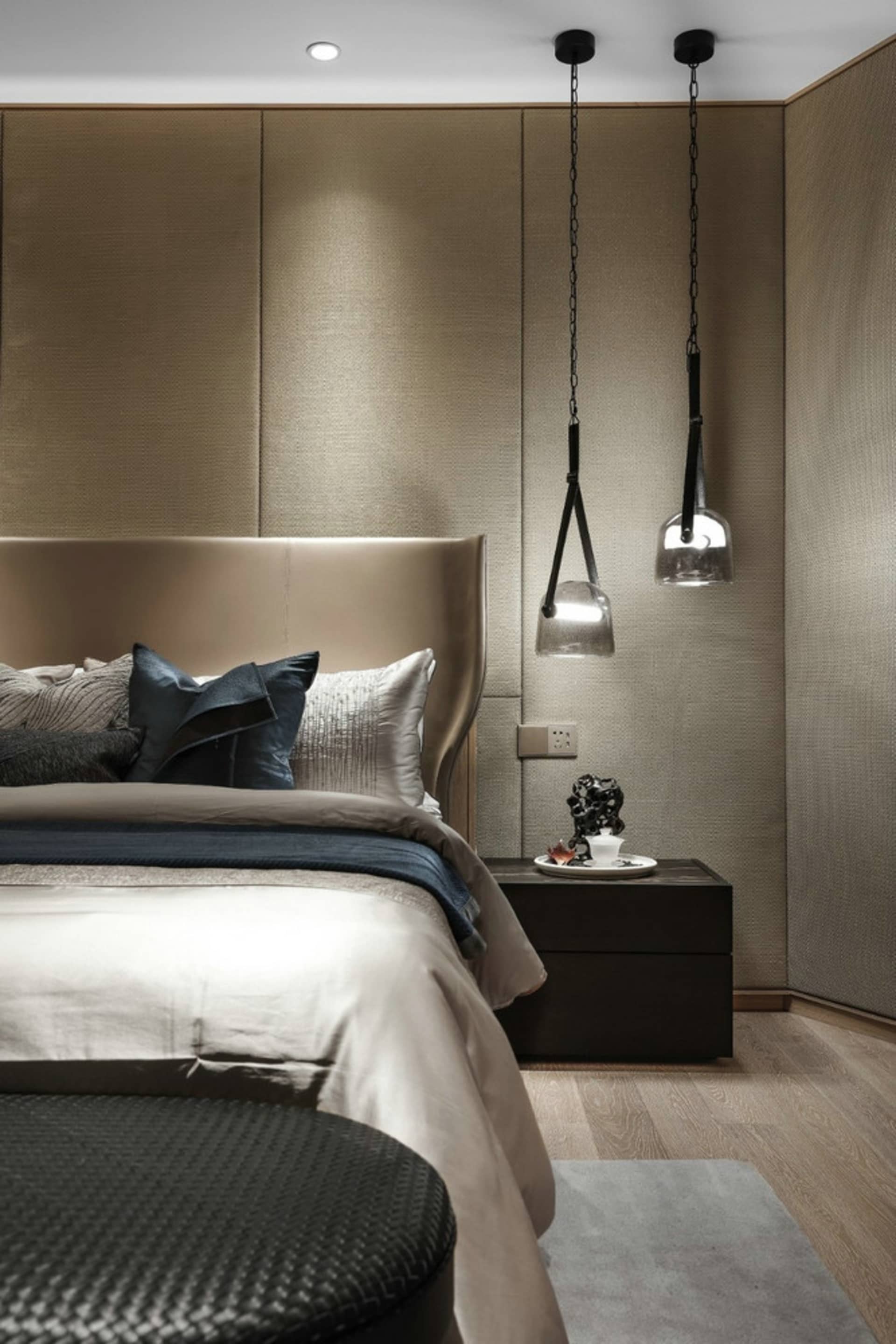A modern bedroom with fabric bedding and glass pendant lights.