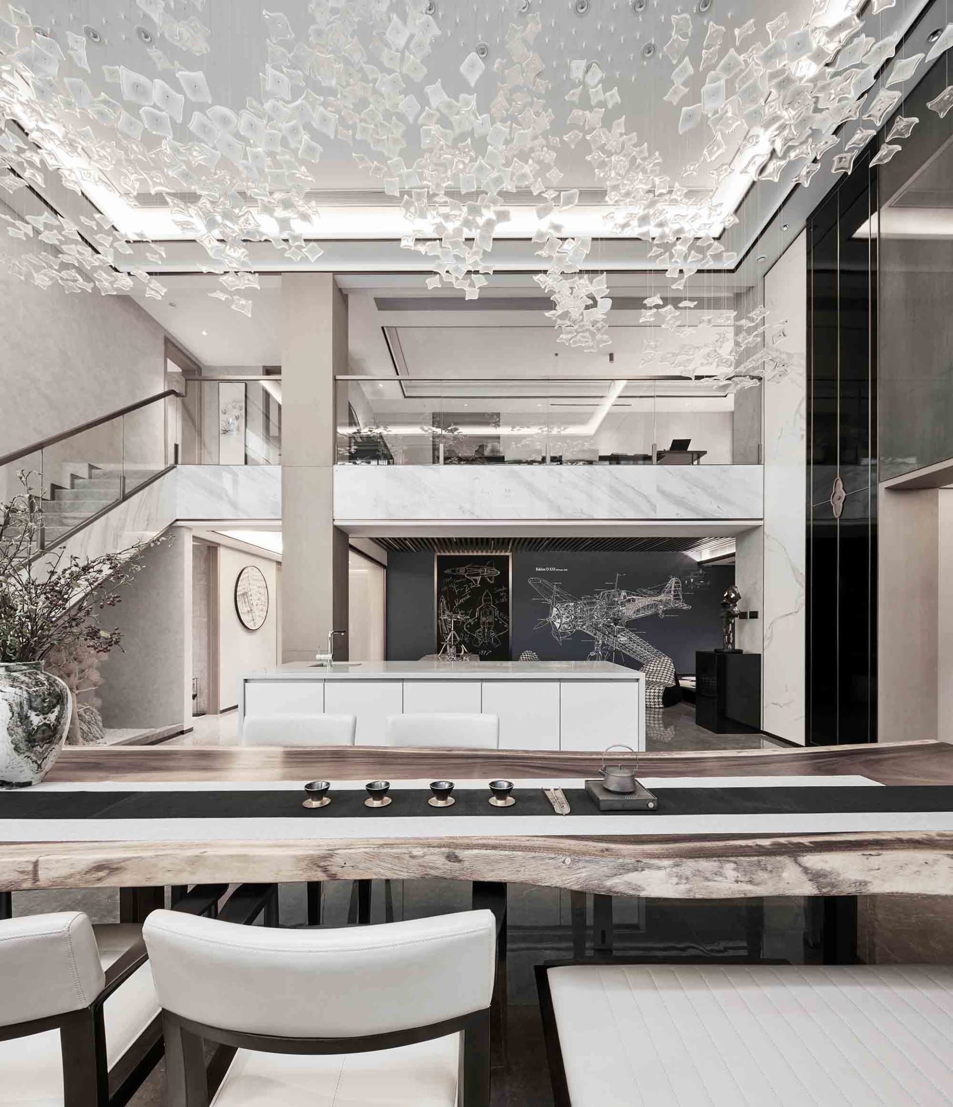 Modern dining room with marble table, white chairs, and glass chandelier