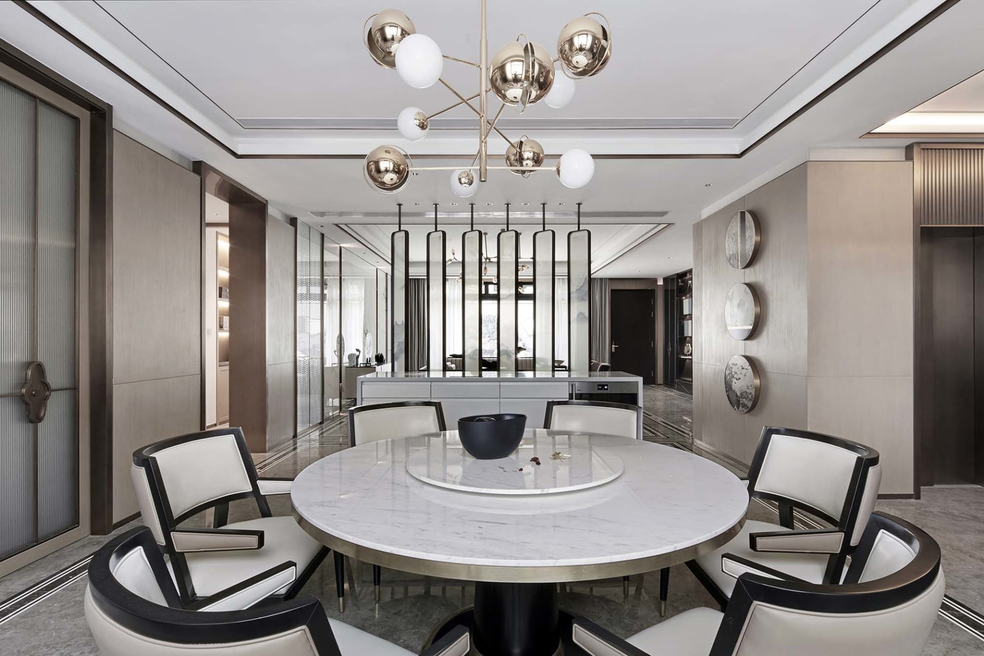 Modern living room with white marble accents, featuring sleek, black and white furniture and a contemporary light fixture.