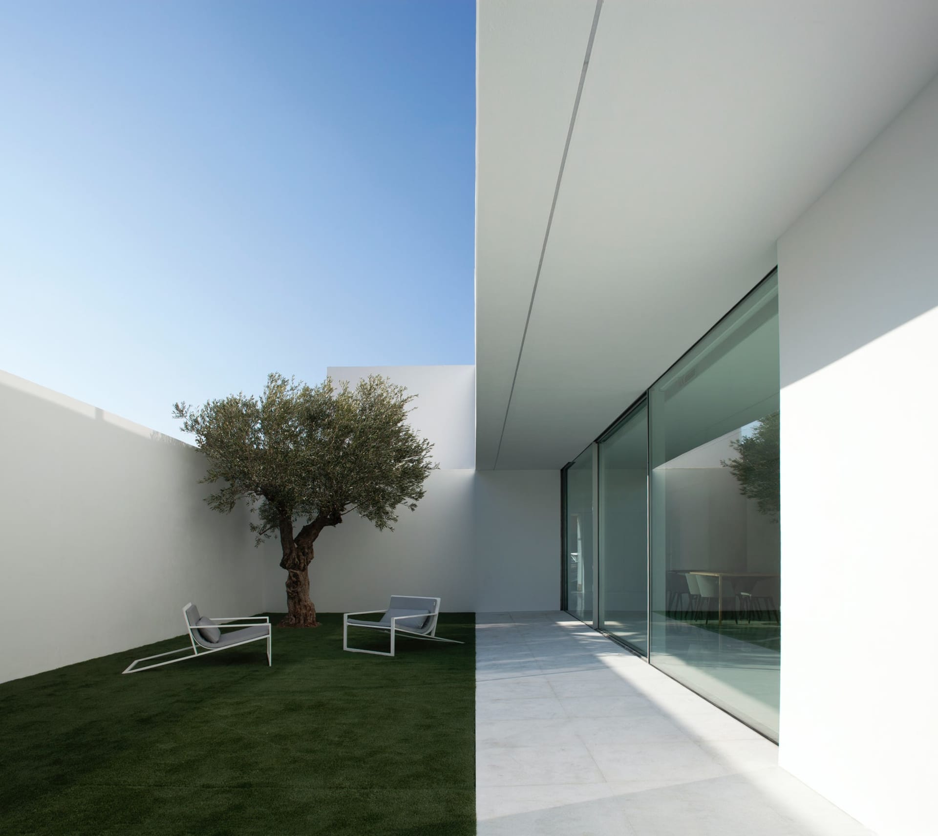 A minimalist modern residential exterior showcases clean lines and a muted color palette, featuring concrete materials and a