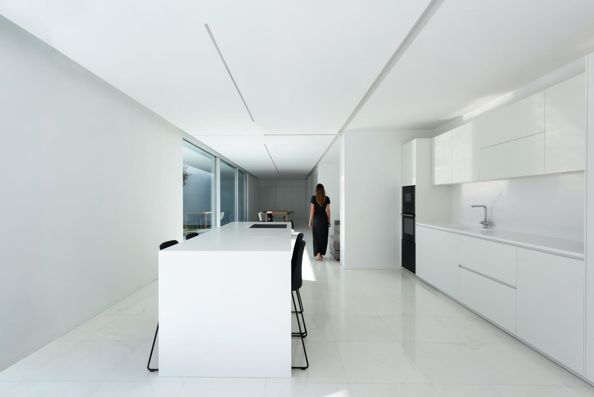 A modern, minimalist kitchen with white marble countertops and white minimalist cabinets.
