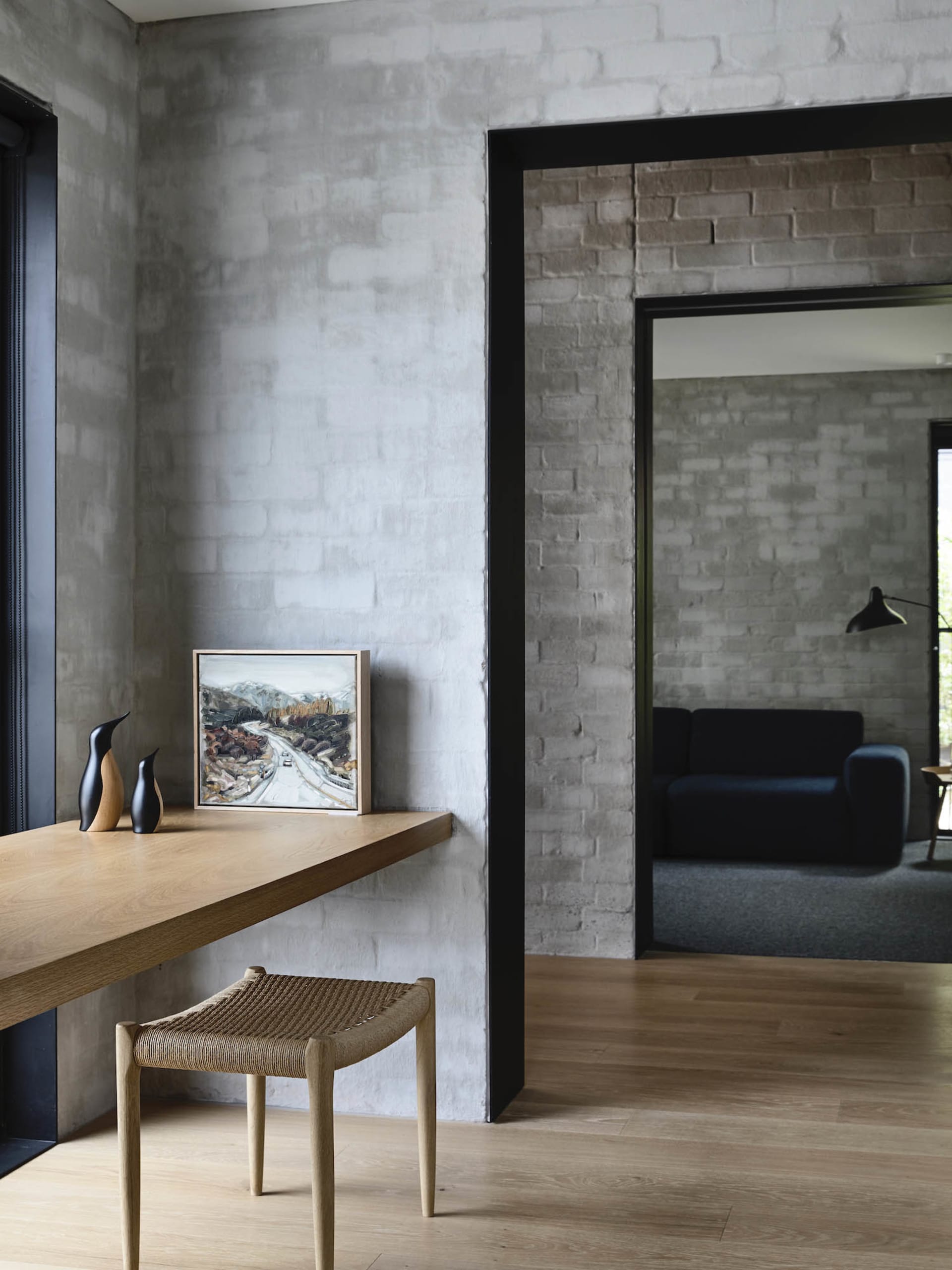 A modern home office with a wooden desk, concrete walls, and brick accents.