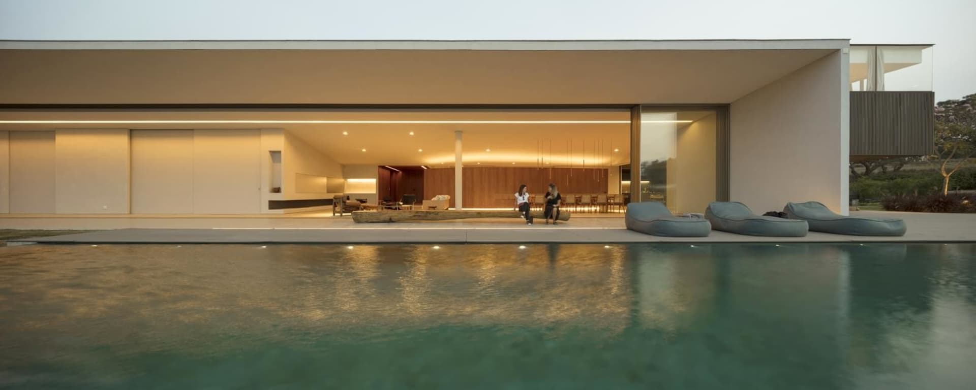Modern house with concrete walls, glass walls, and wood furniture.
