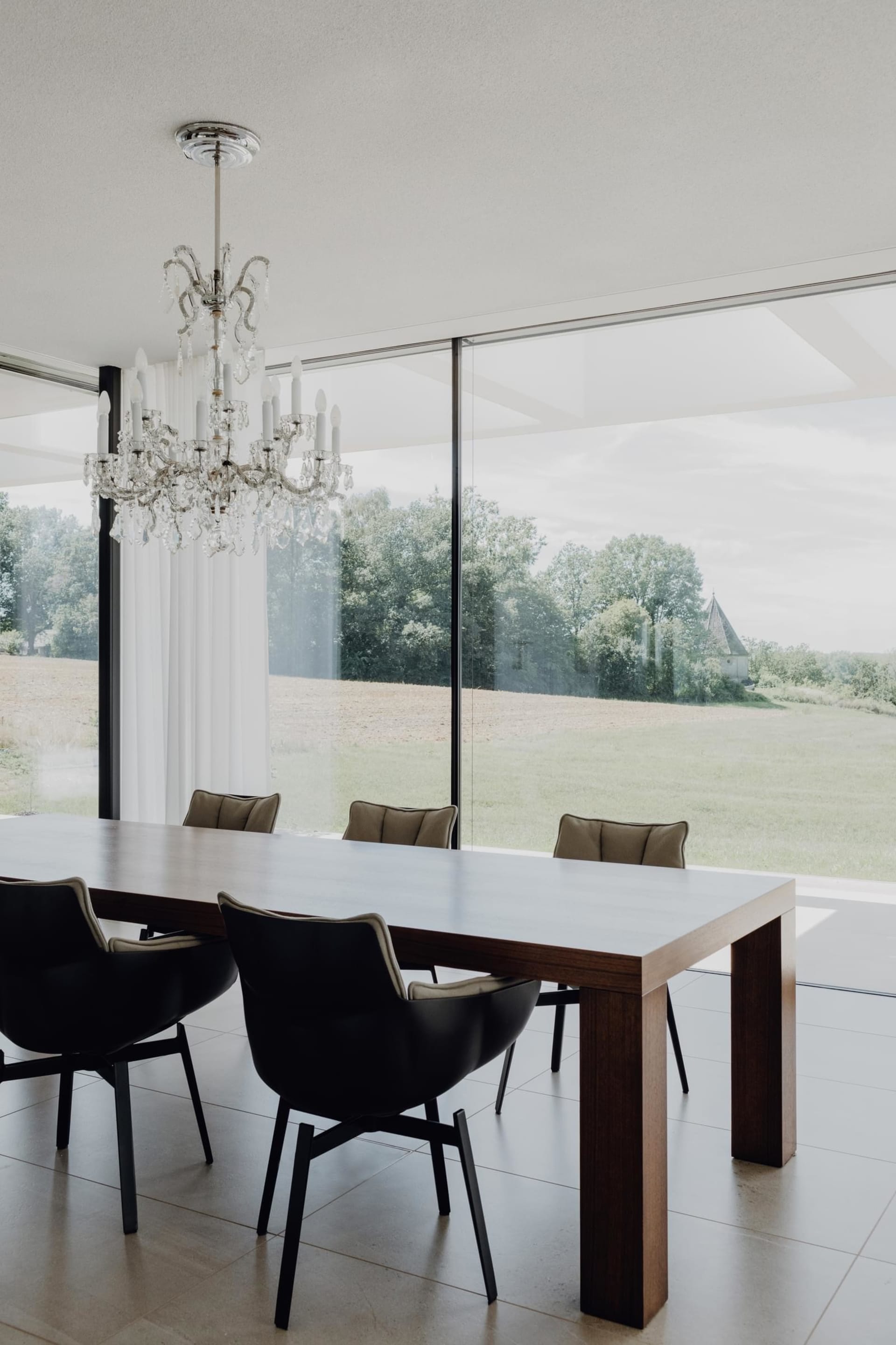Modern minimalist dining room with a wooden table and black chairs.